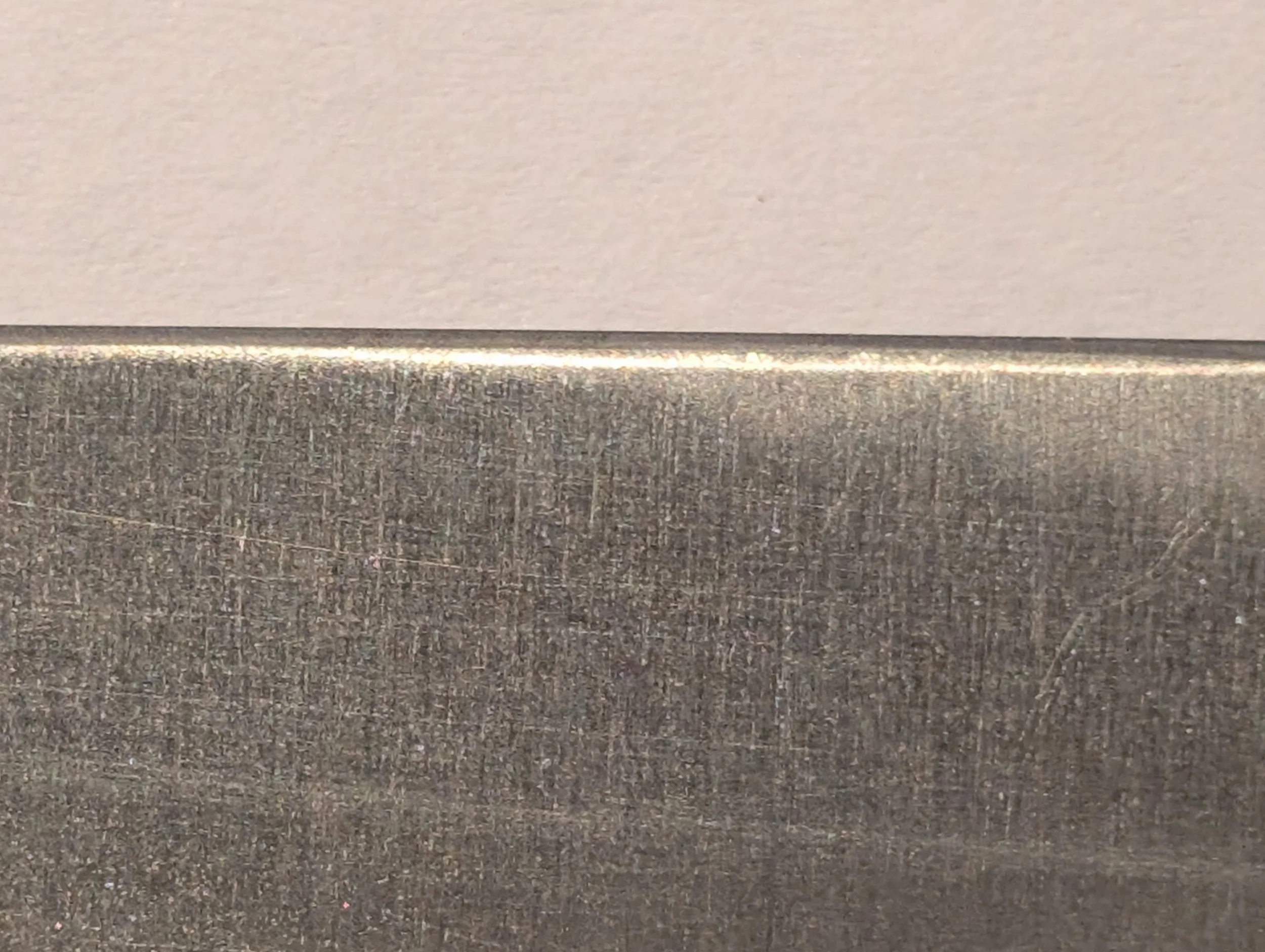 Close-up of a metal blade edge against a plain background.