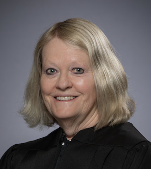 Photo of a smiling woman with blonde hair wearing a black judicial robe.