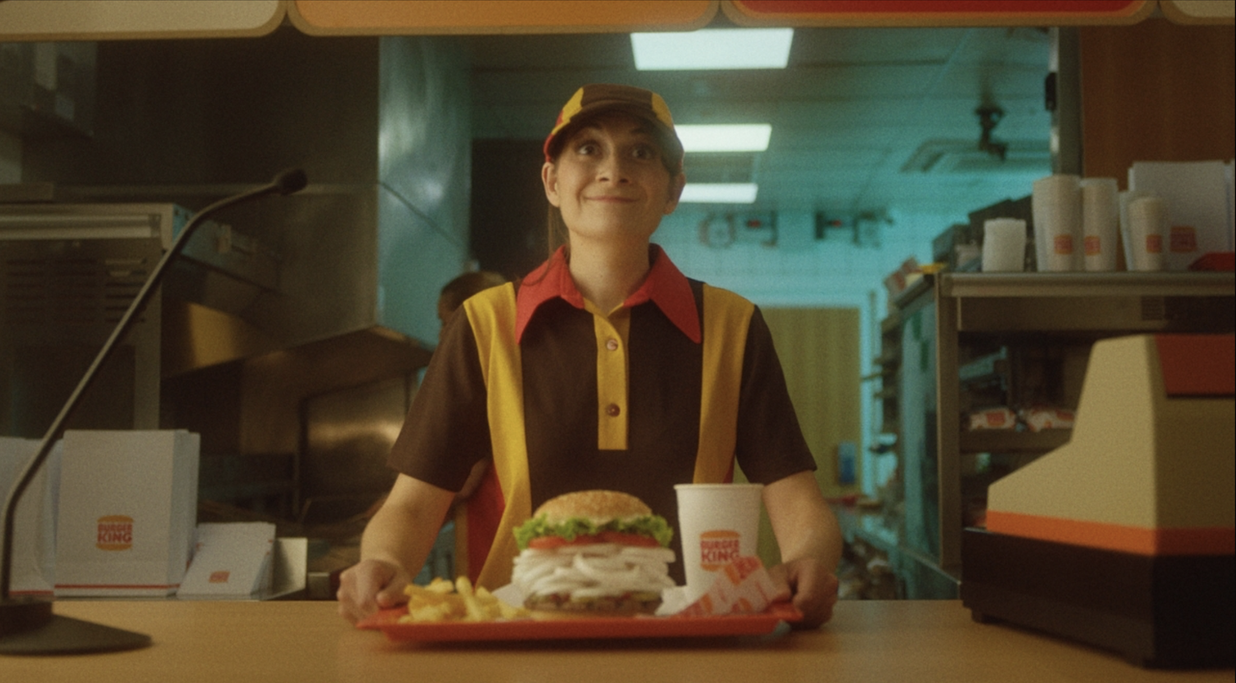Burger King ad spot commercial Fast food restaurant worker holding a tray with a burger, fries, and a drink at the counter.