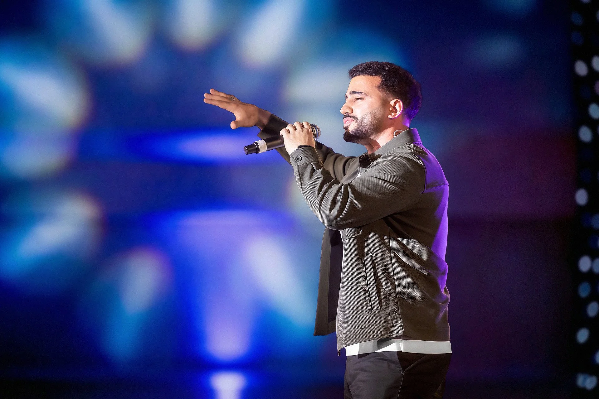 Mohamed Tarek performing nasheed live on stage at ILMCON25 with a custom LED backdrop, professional lighting, and sound design by Samson Productions