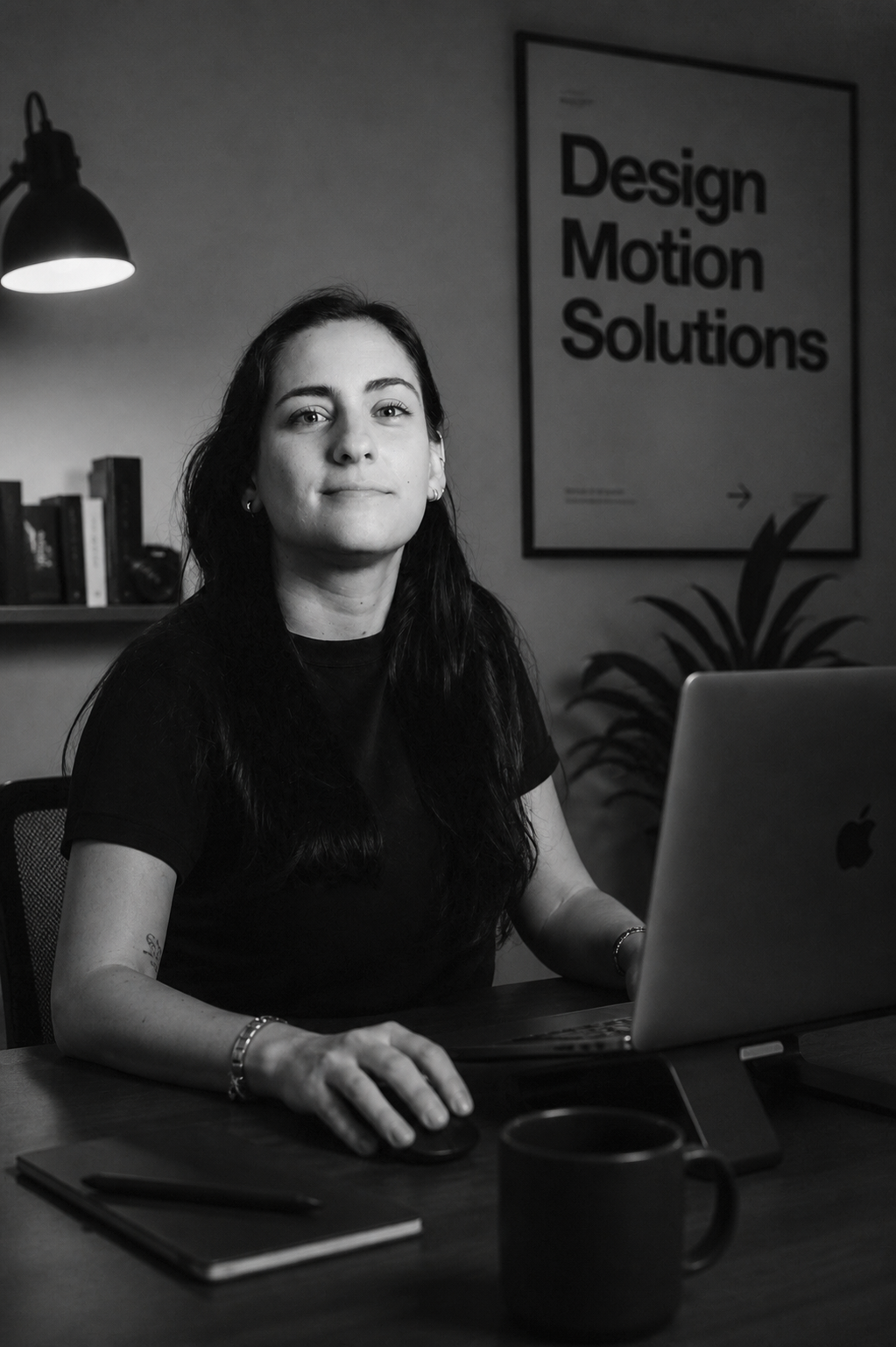Mujer en una oficina, sentado frente a una computadora portátil. En el fondo, cartel que dice "Design Motion Solutions".