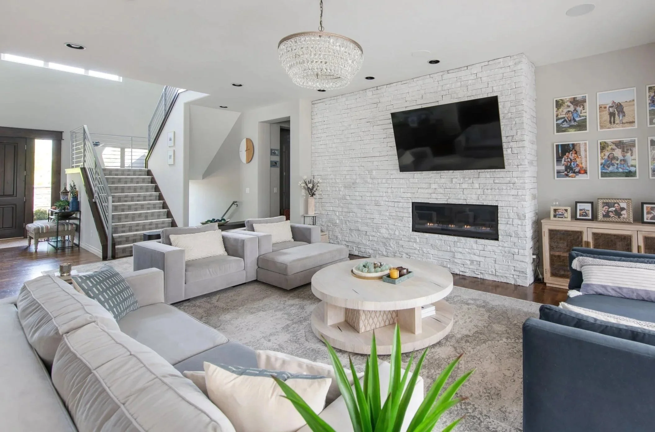 Bright modern organic living room with limewashed brick fireplace, mounted TV, modern RH sofa, arhaus coffee table.  Pattern carpet on stairs. Designed by Haveli Designs in Colorado. Timeless Family Friendly design and livable luxury.