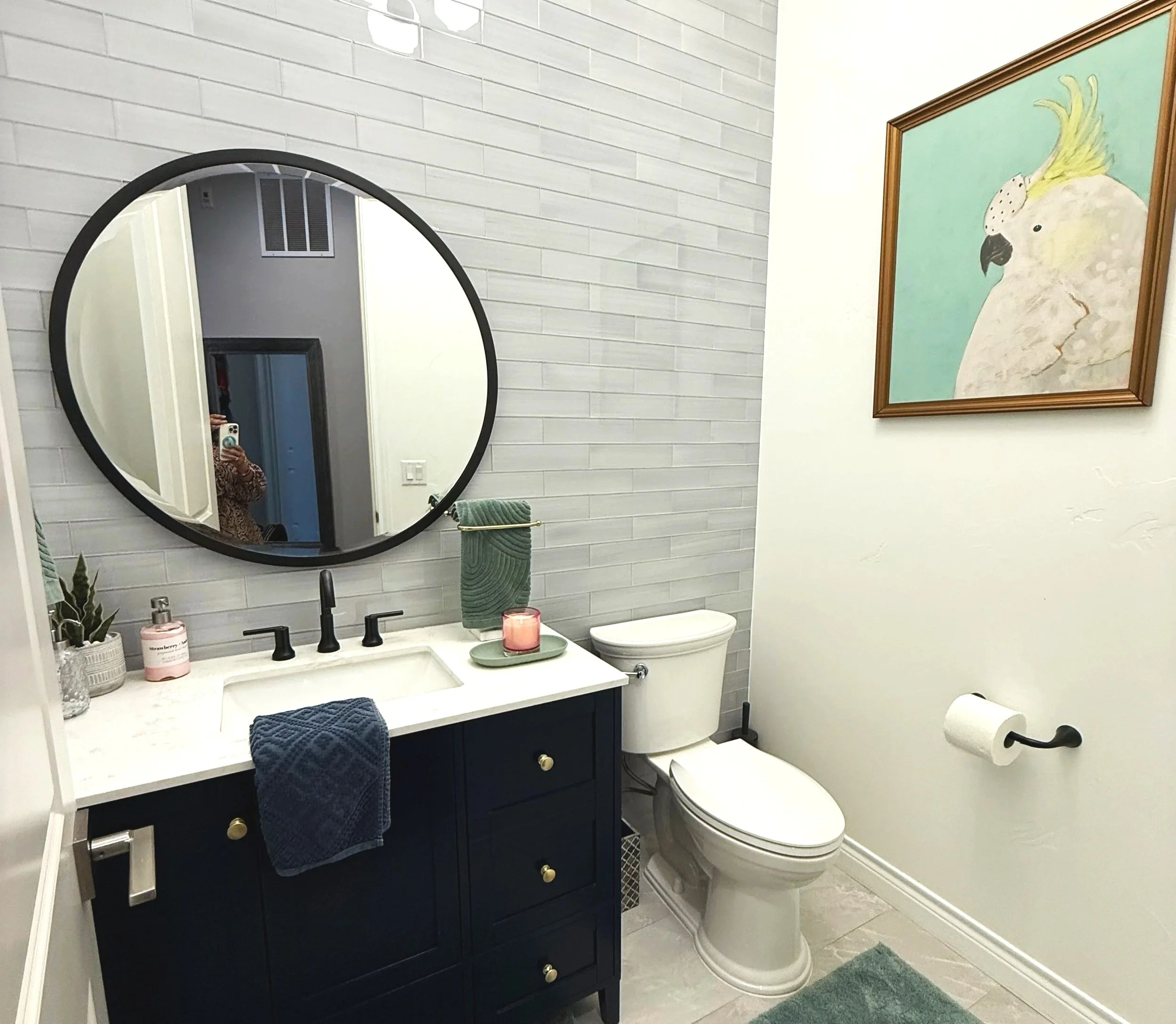 Powder room renovation for busy family of two boys. Pottery Barn vanity and mirror.  Glass tiled wall and clean bright aesthetic. Family Friendly timelss livable luxury style design. Whimsical art on the wall.