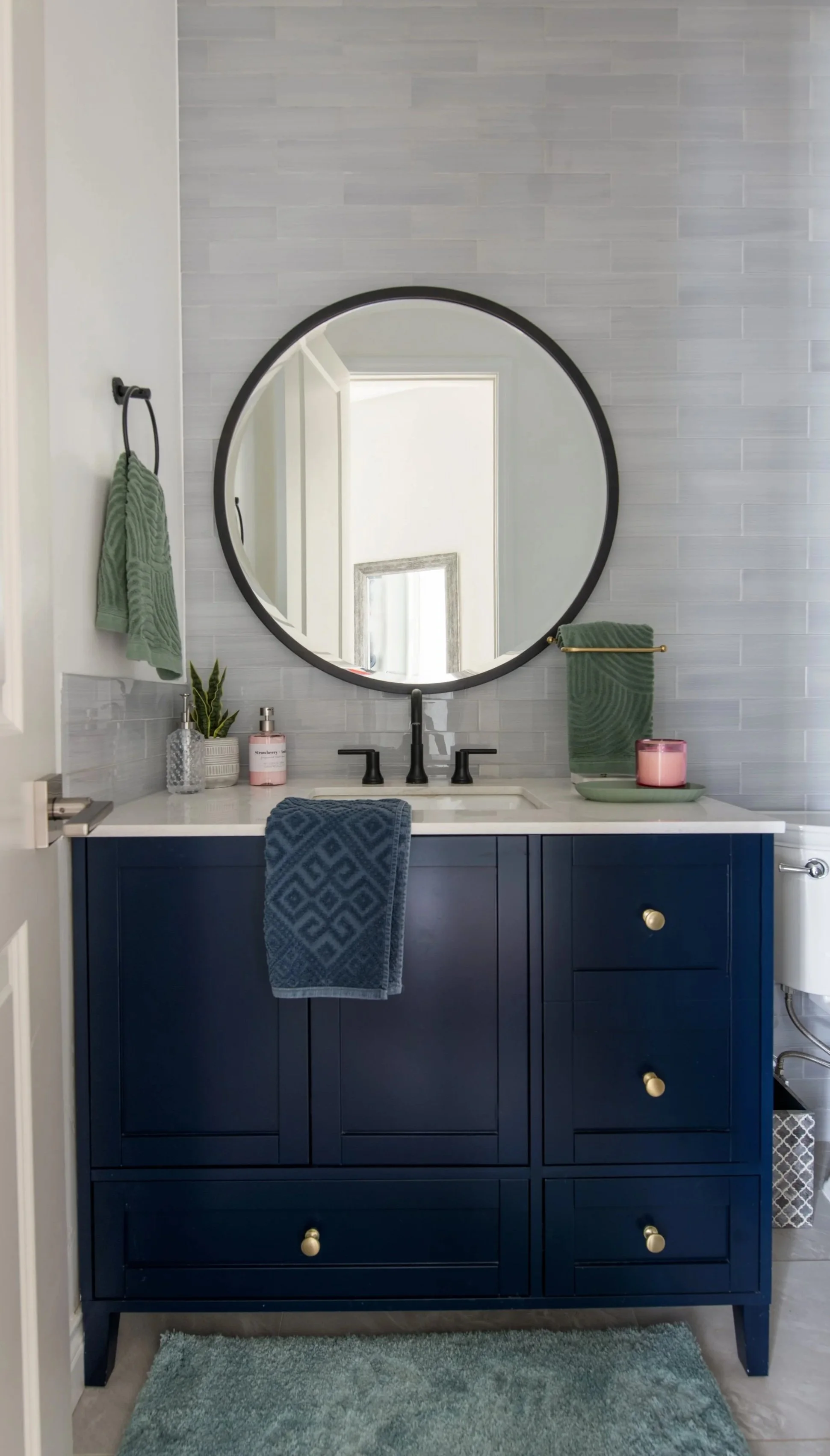 Powder room renovation for busy family of two boys. Pottery Barn vanity and mirror.  Glass tiled wall and clean bright aesthetic. Family Friendly timelss livable luxury style design.