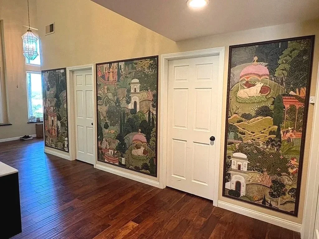 Four panels with colorful nature and architecture scenes, two white interior doors, hardwood floor, and a window with a hanging lantern nearby.Foyer entry renovation with south asian fusion style. Designed by haveli designs in colorado. Wall murals w
