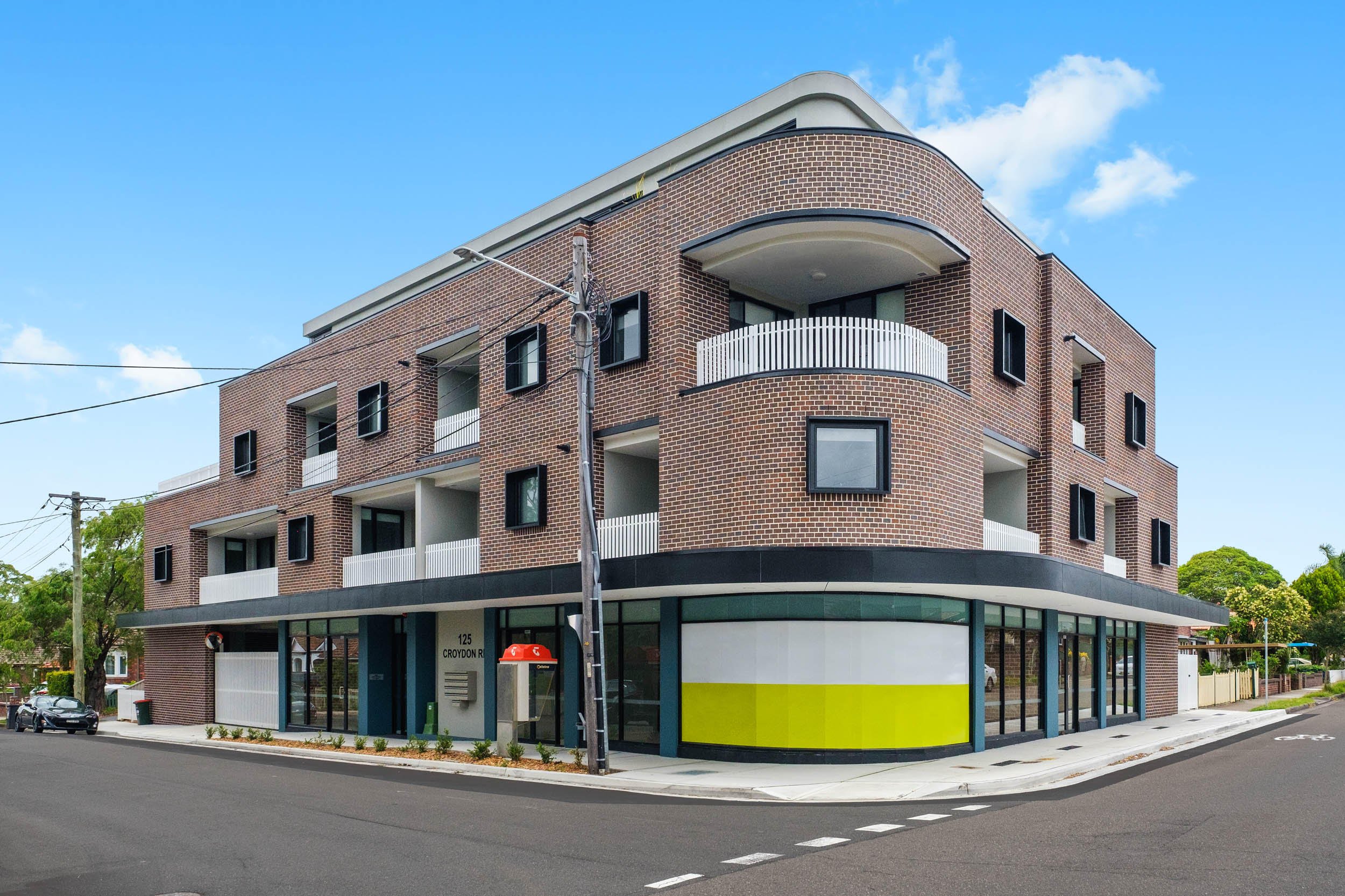 Modern brick apartment building with balconies on a street corner.