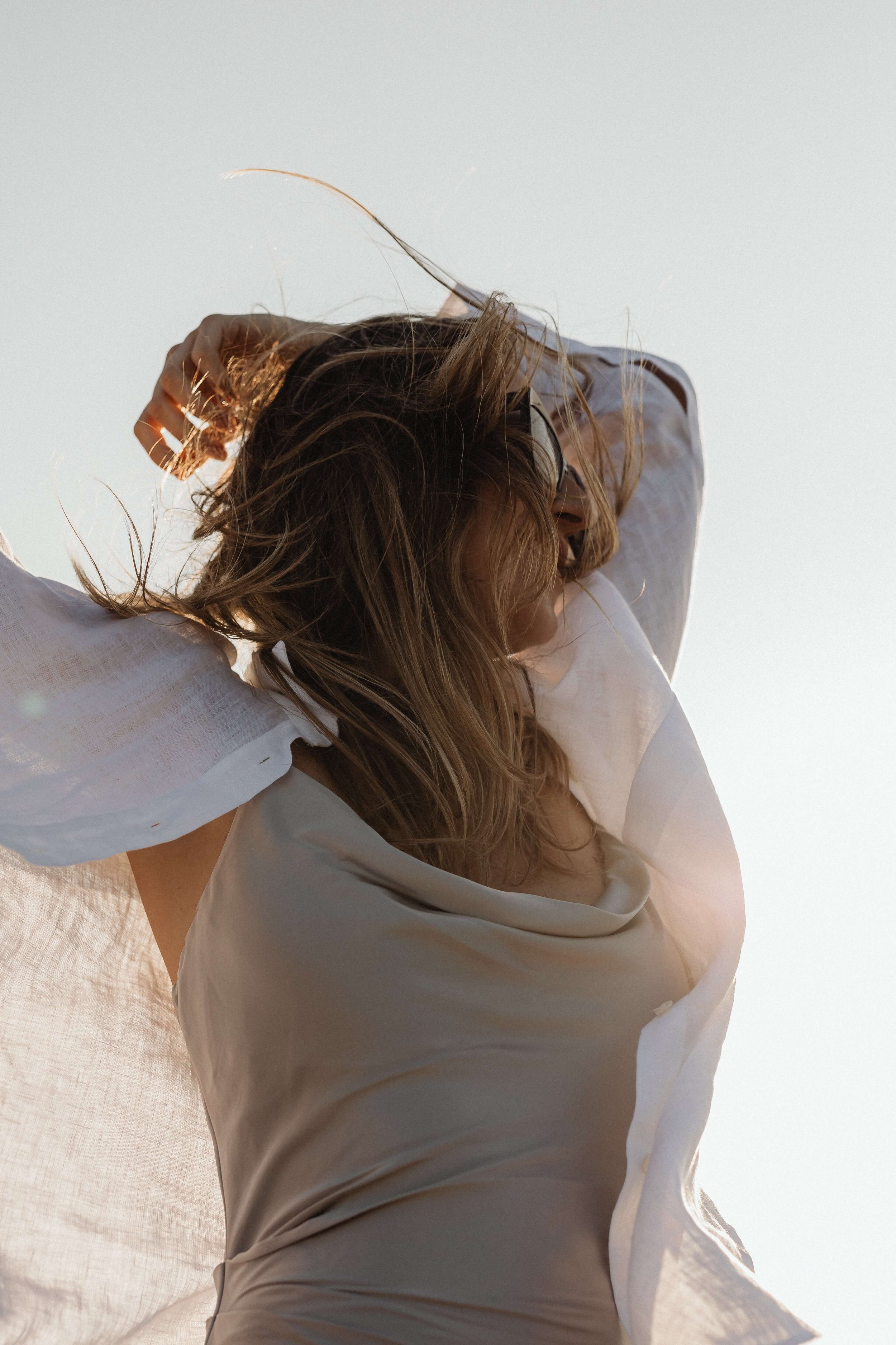 Woman with effortlessly styled hair enjoying a sunny, breezy day—capturing the relaxed vibe of Valos Hair Salon