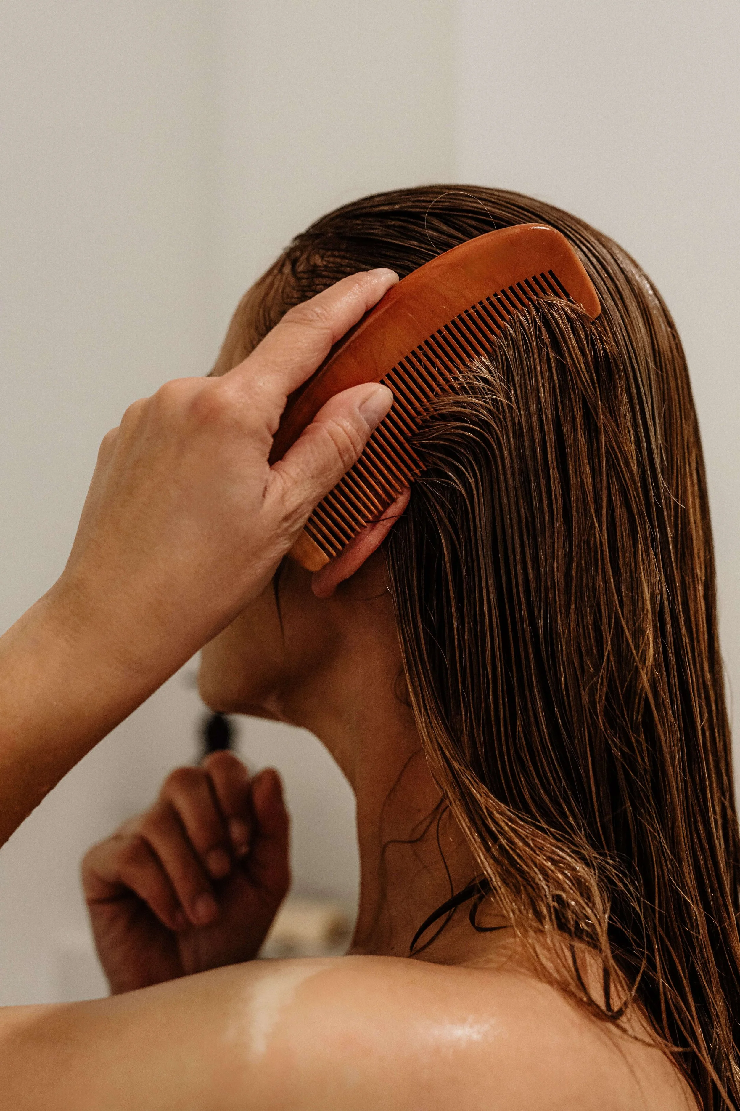 lose-up of woman combing through wet hair, highlighting hair care and self-care at Valos Hair Studio