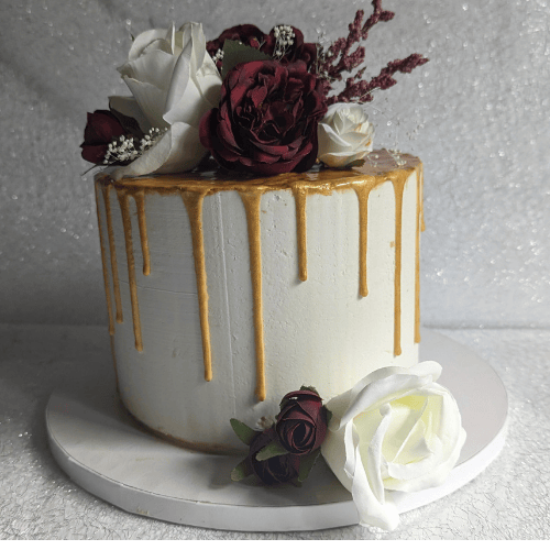 Elegant custom anniversary cake with gold and white floral design, handcrafted by Fort Washington bakery A Matter of Cake
