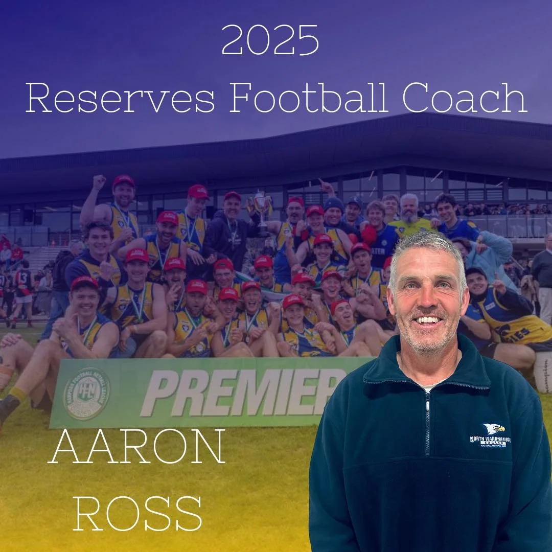 Celebrating a football team with medals and a trophy on a field at a stadium, with a man standing in front wearing a dark jacket with a logo, in front of a large banner reading 'PREMIER'. Overlaid text says '2025 Reserves Football Coach' and 'AARON ROSS'.