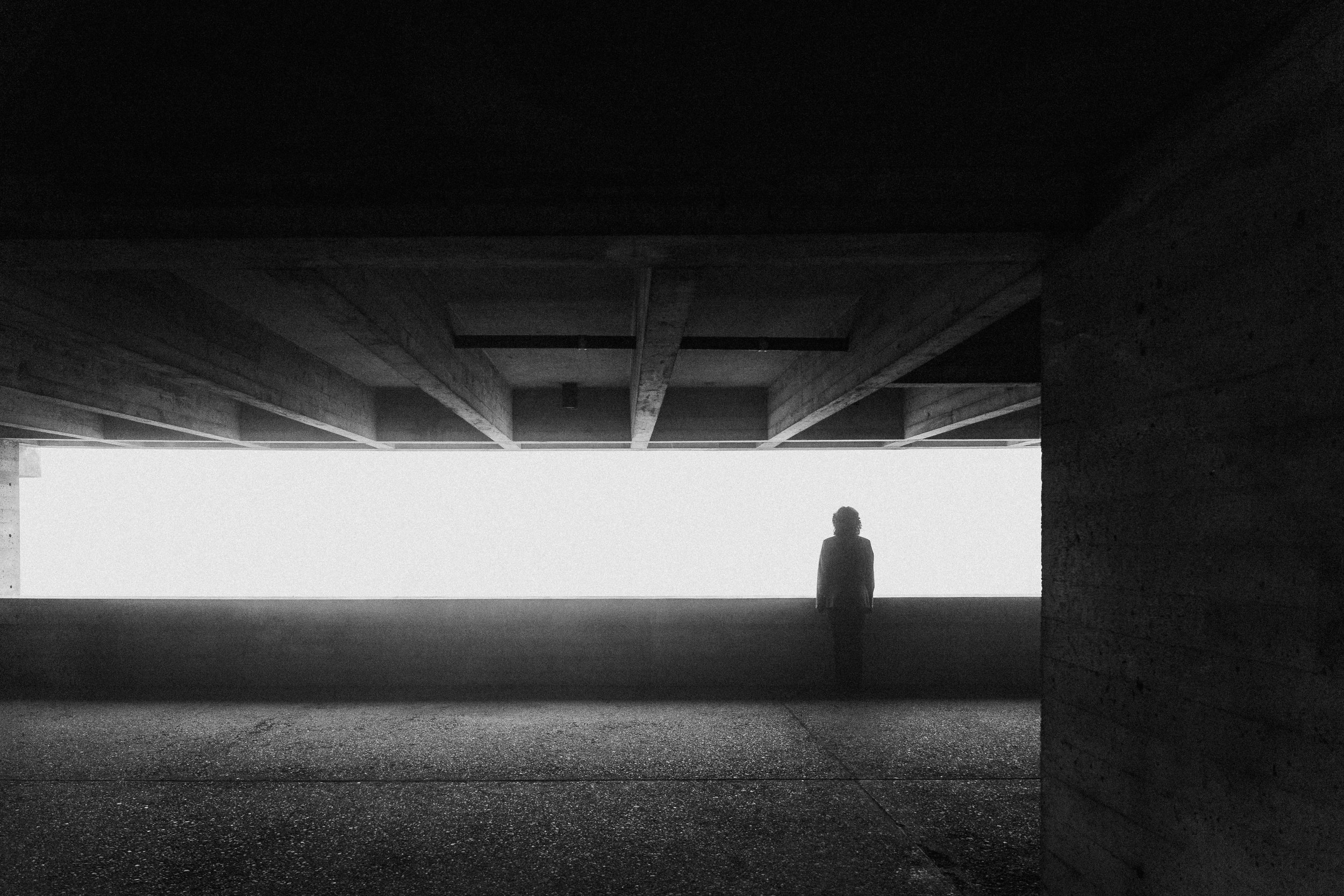 silhouette of a person under a concrete structure