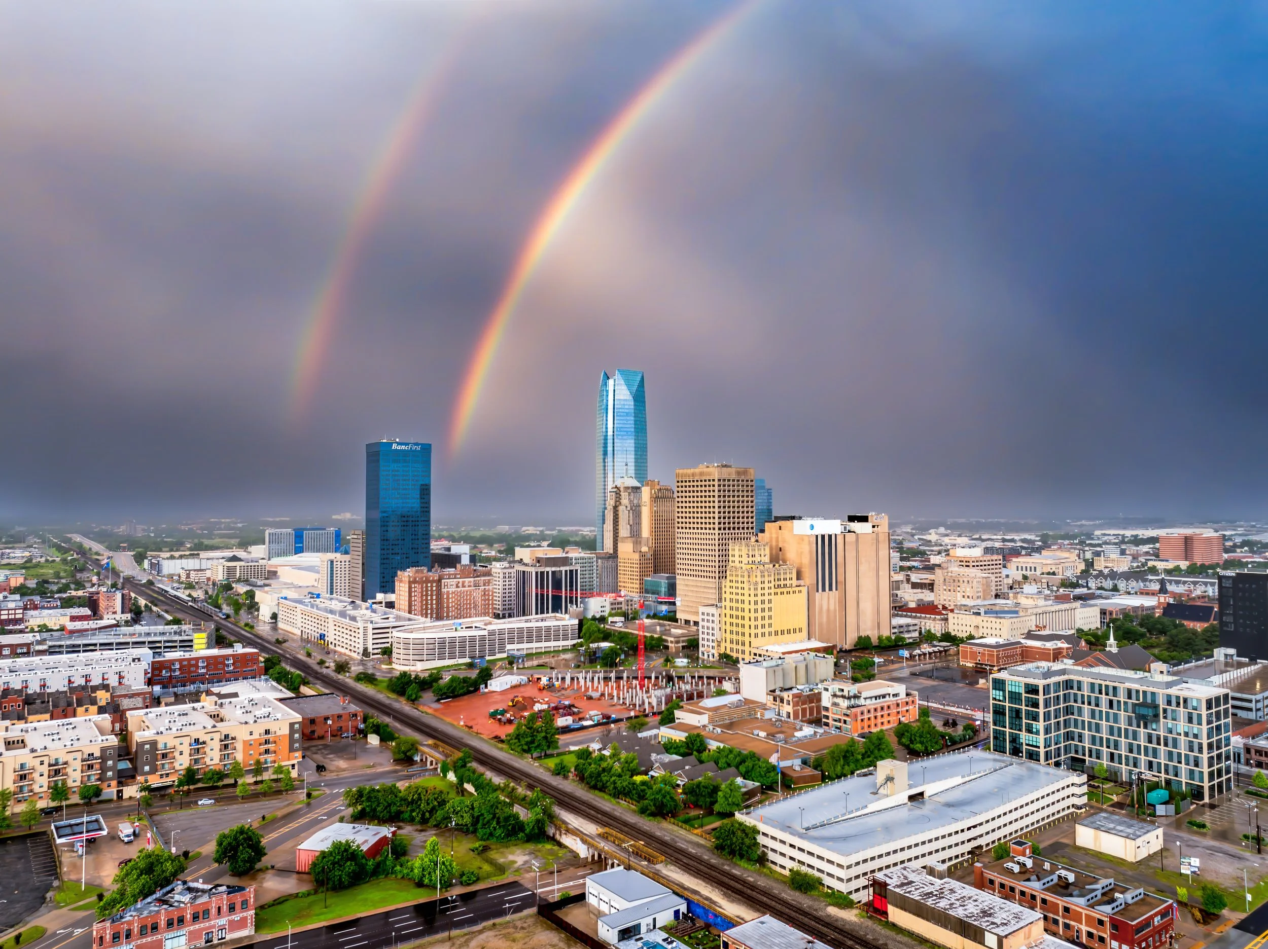 Cityscape of Fort Worth, Texas with skyscrapers, rainbow in stormy sky, railway, and urban buildings.