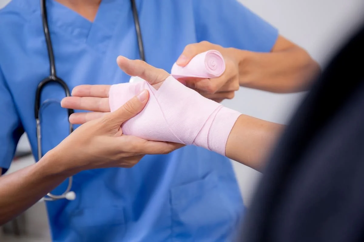 Close-up of nurse bandaging a patient's hand, representing wound care and recovery support in home nursing in Australia.