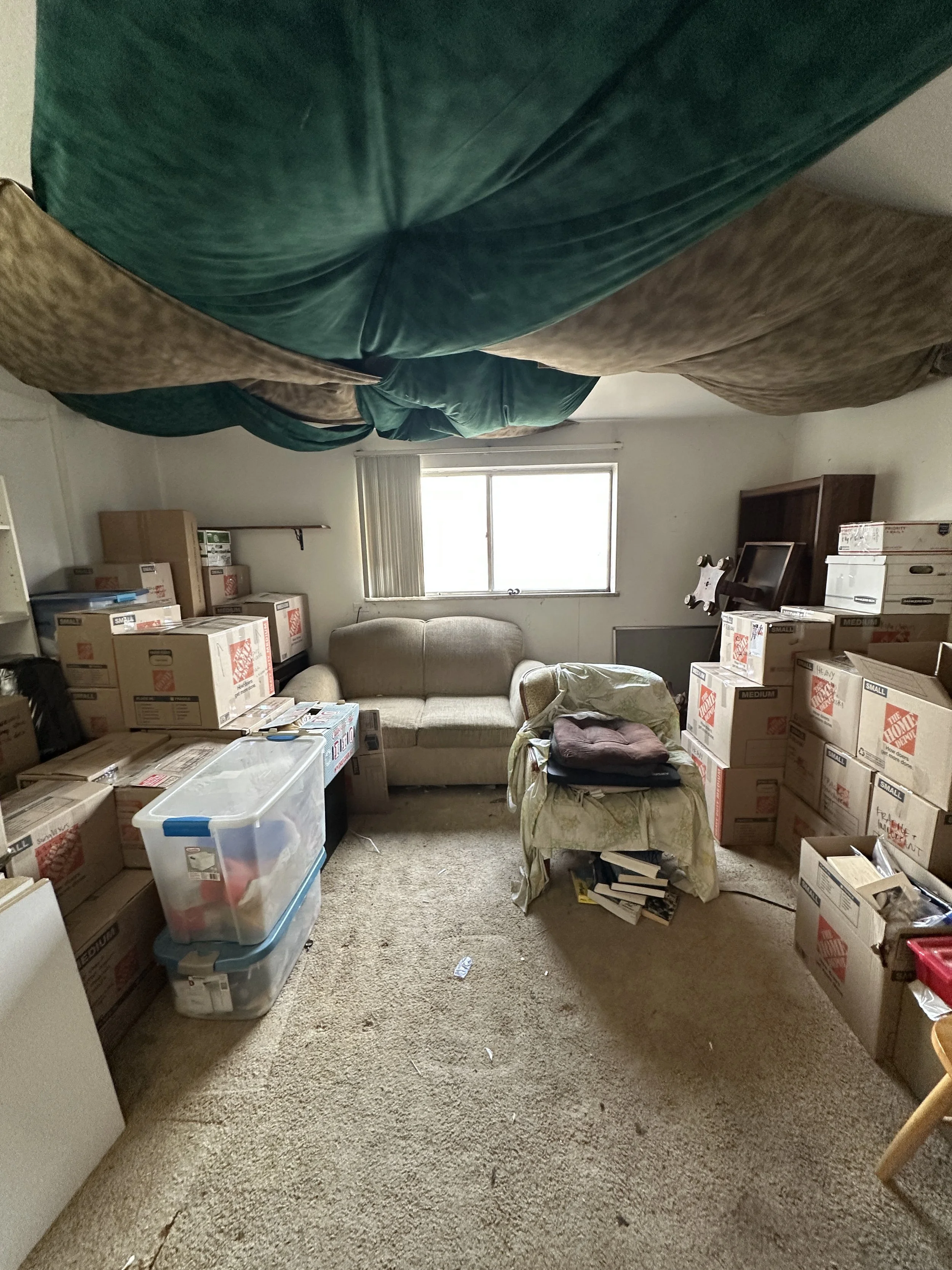 After image of a professionally organized, decluttered, and packed living room after a project day with Strategic Spaces. The floor is clear of items, with clear walkways and belongings packed and stacked on the edges of the room.