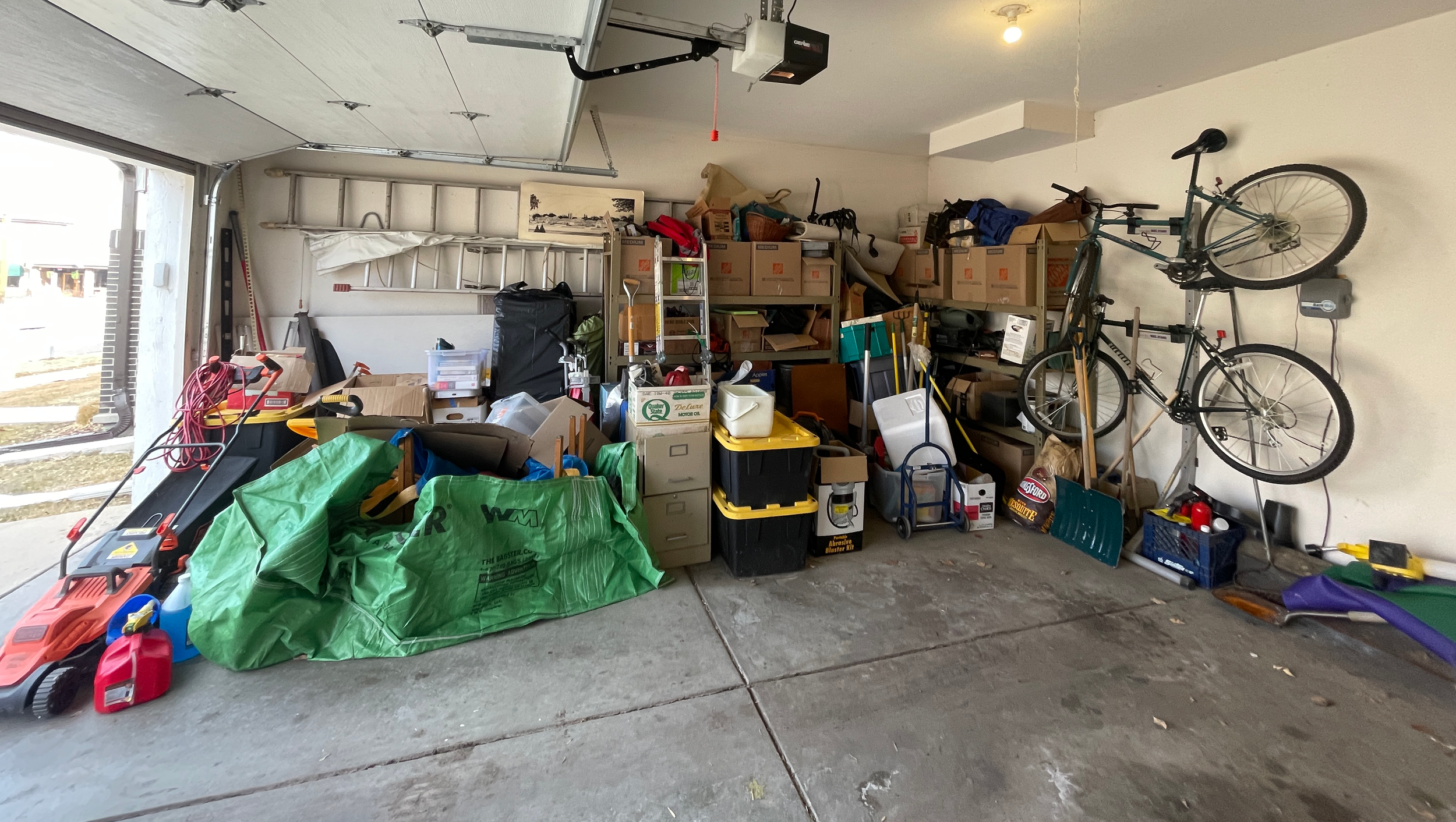 Before image of a two car garage that has belongings piled up in one side of the space.