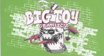 Graffiti-style mural on a green brick wall with the words 'Big Toy Graphics' and a cartoon skull mascot holding a spray paint can.