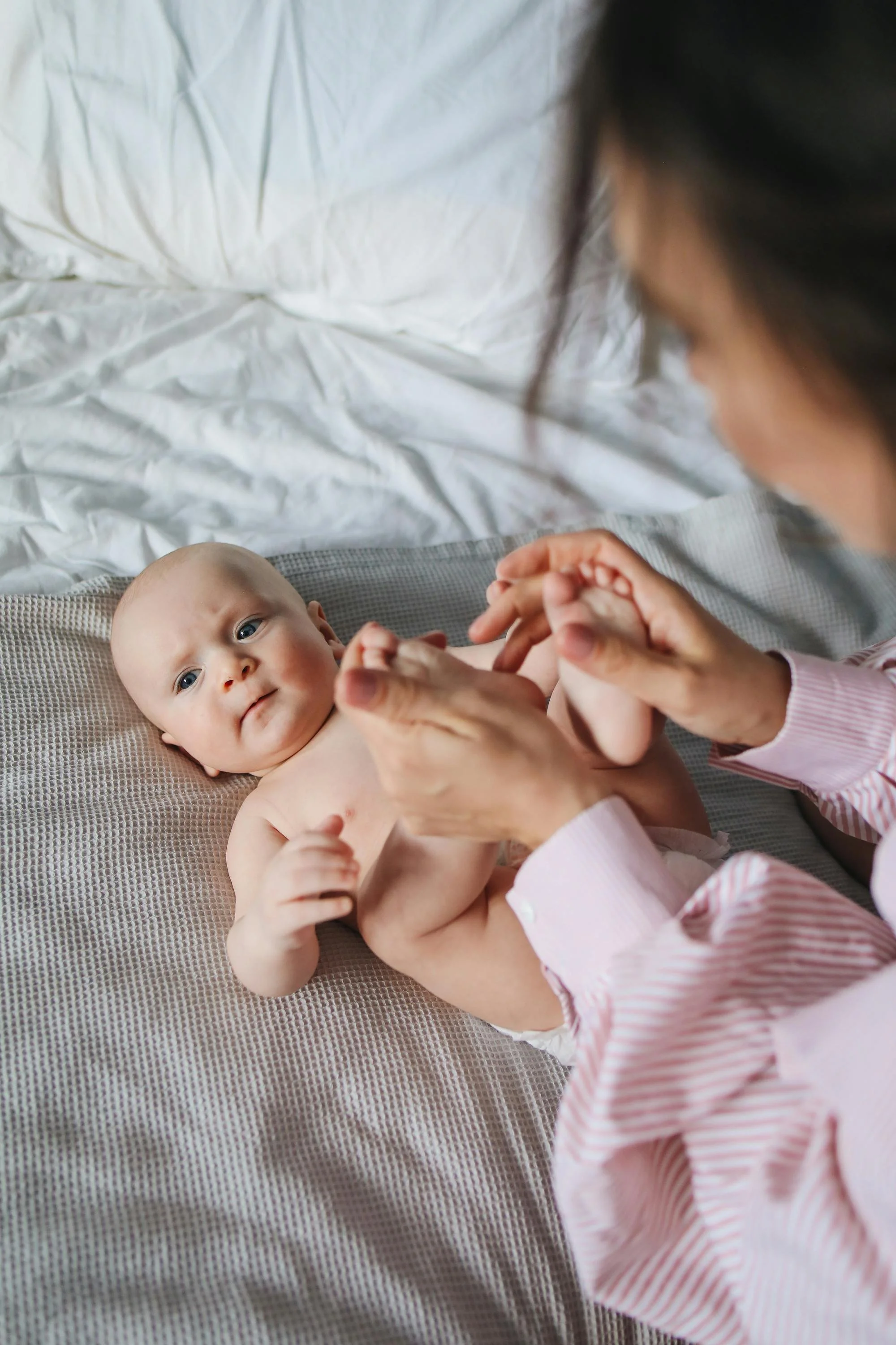 A mum lifting babies feet to help roll