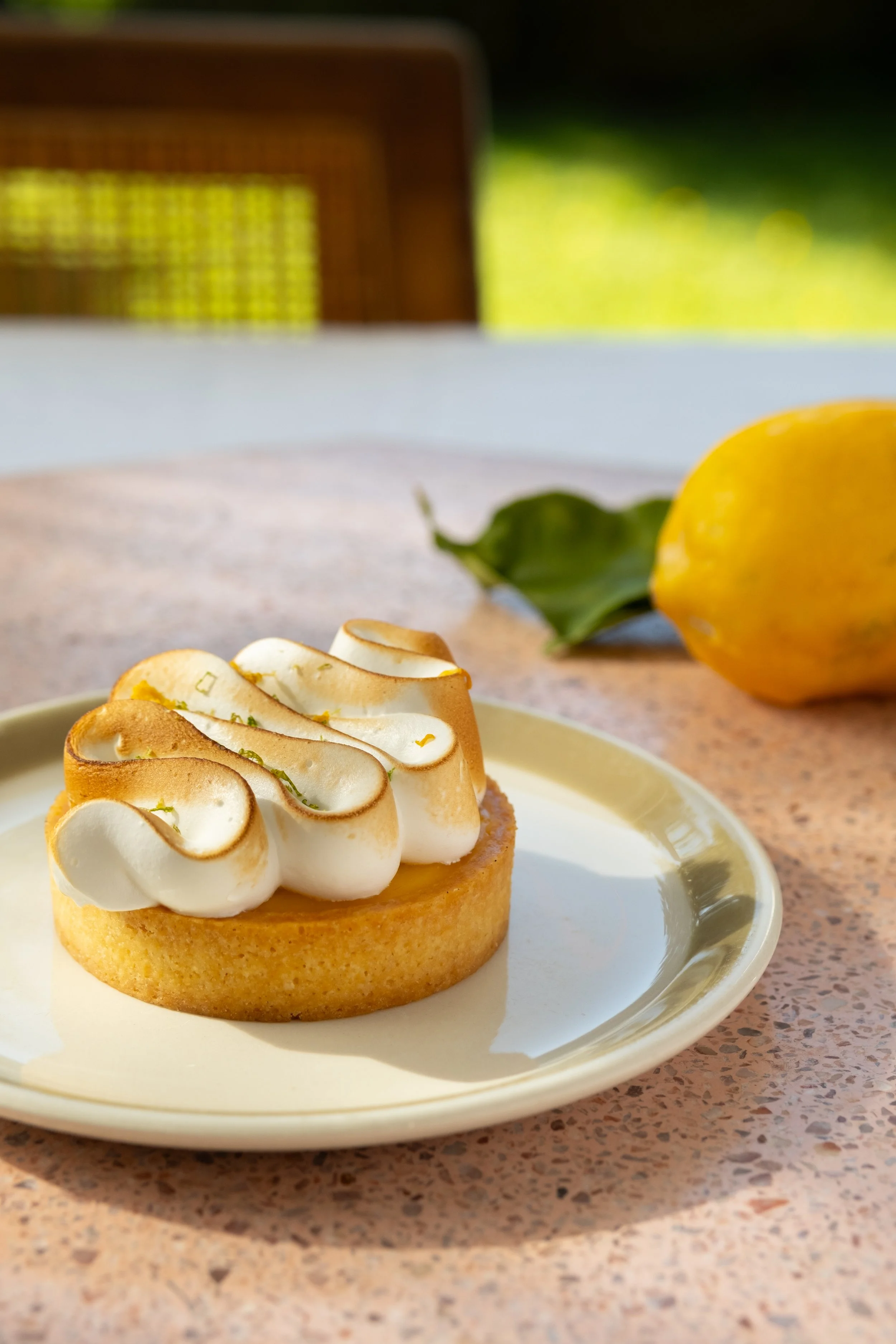 Lemon meringue tart on plate with lemon in the background