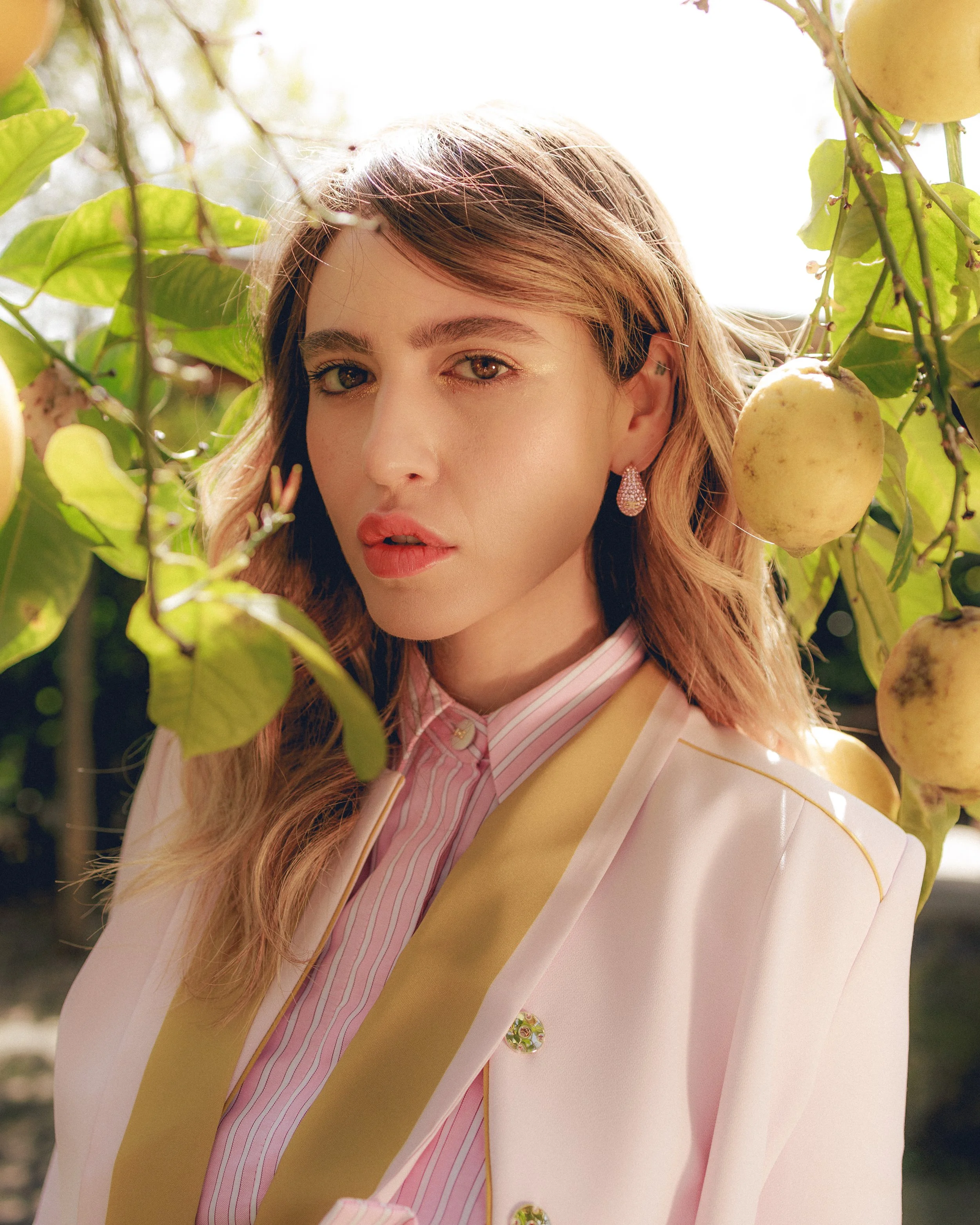 Donna con abbigliamento elegante tra foglie e limoni.