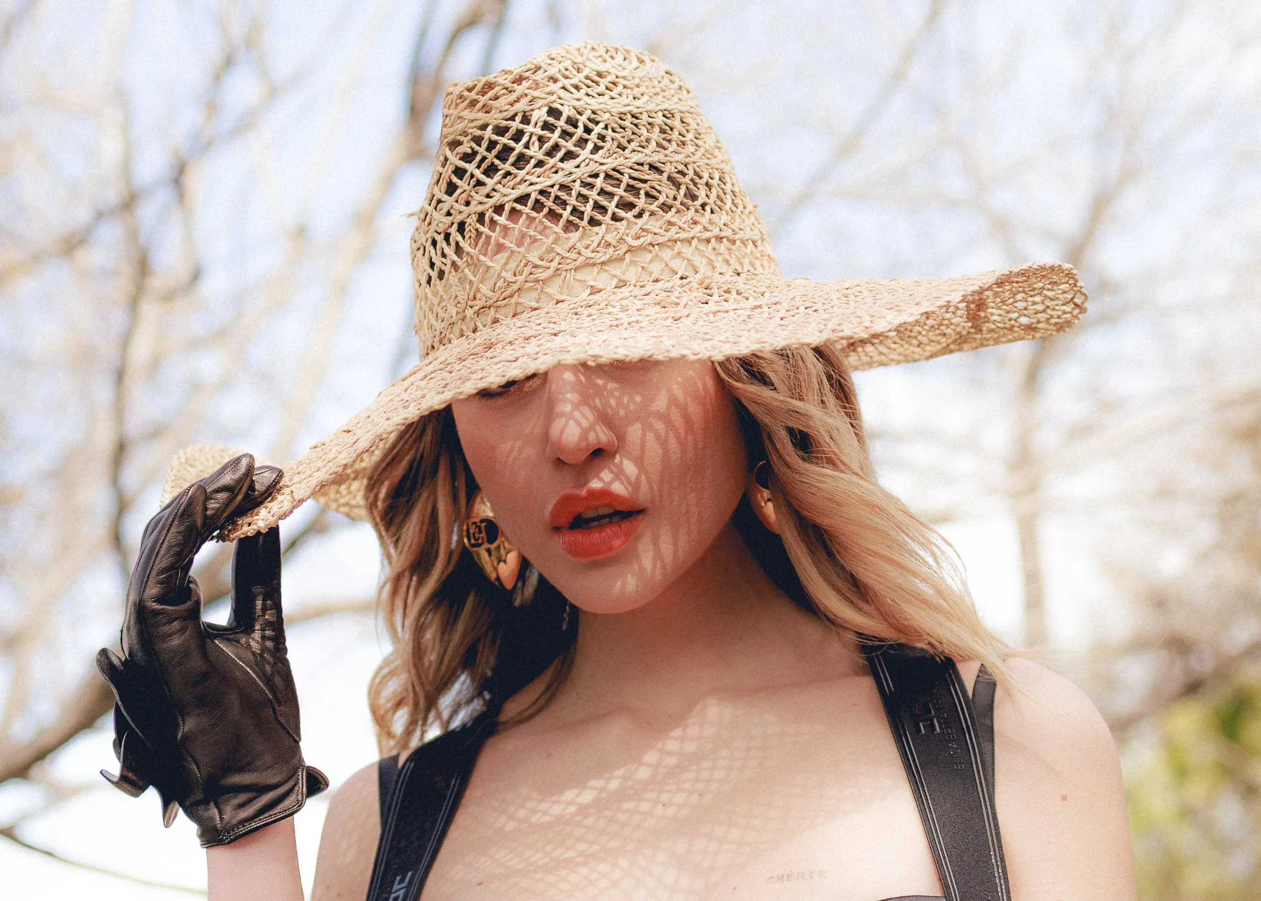 Donna con cappello di paglia e guanti neri.