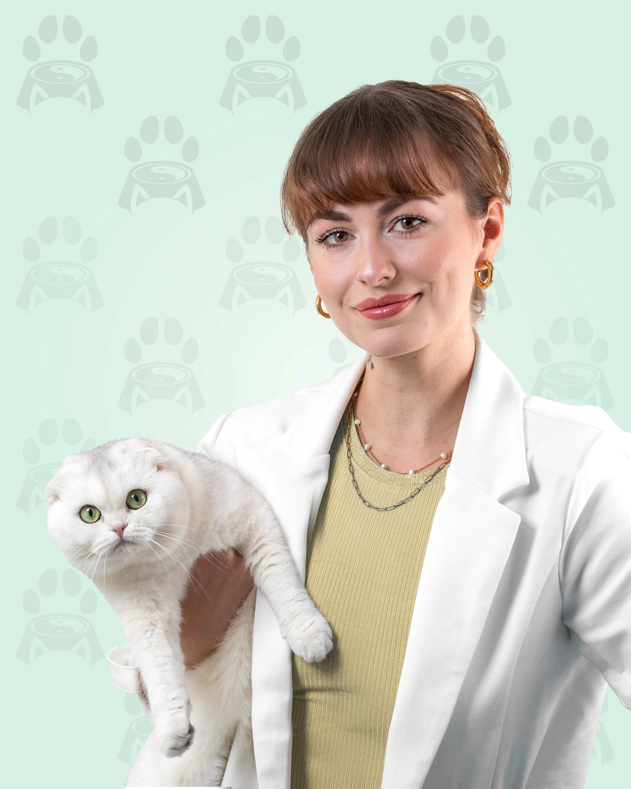 A woman wearing a white coat holding a white cat with green eyes against a light green background.