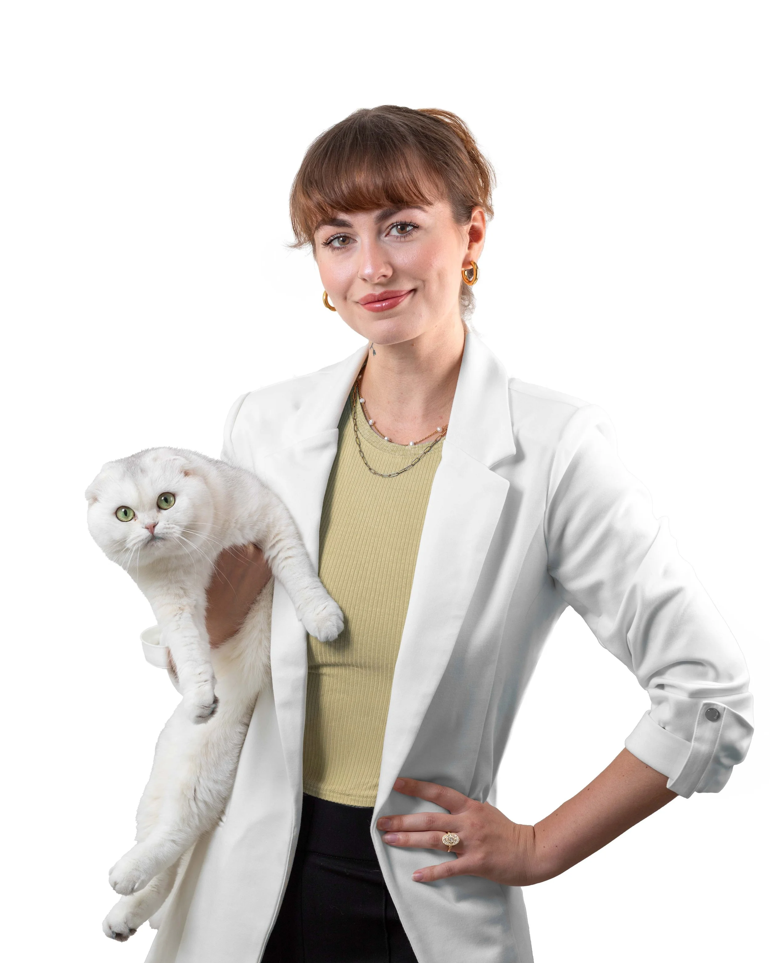 A woman with short brown hair, wearing a white blazer and earrings, is holding a white cat with green eyes against a plain white background.