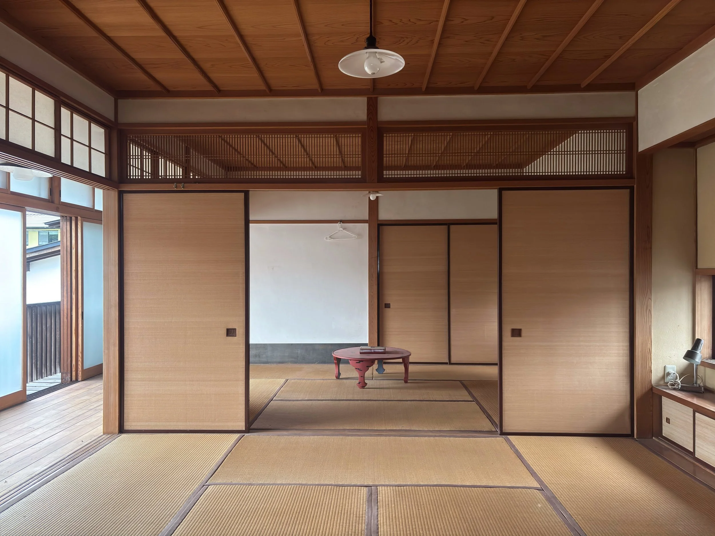 Traditional Japanese tatami room with sliding wooden doors, a small round table, and natural light coming through shoji screens.