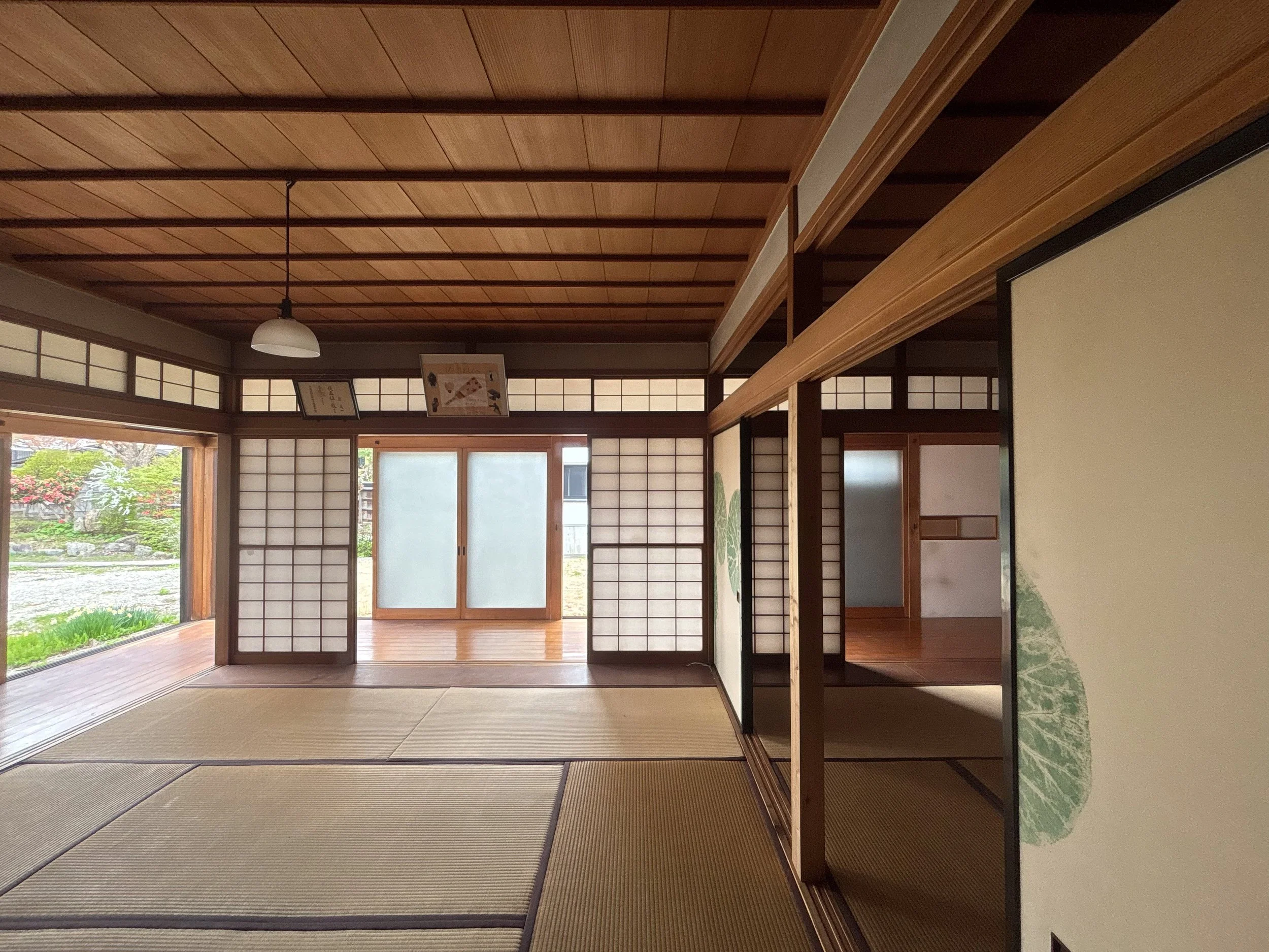 Interior of a traditional Japanese room with tatami mats, sliding shoji doors, and wooden ceiling and beams.