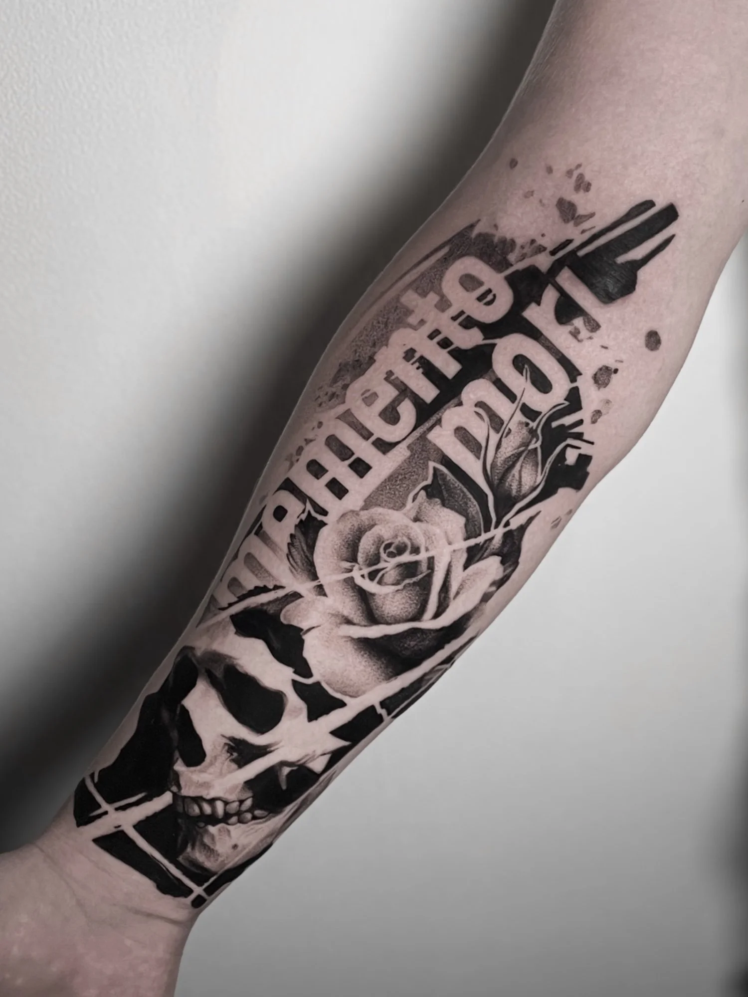Black and gray tattoo sleeve on person's arm featuring flowers and skulls.