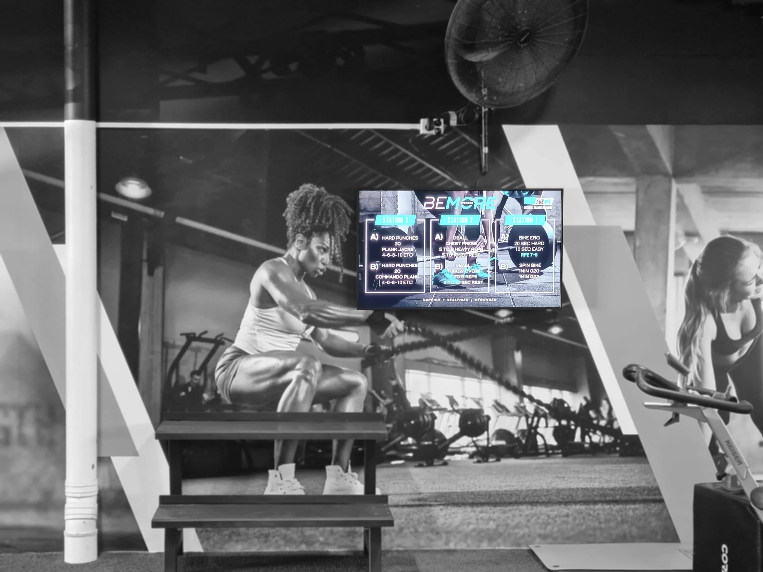 Gym display showing three workout stations beside a spin bike at Bemore Fitness, Perth.