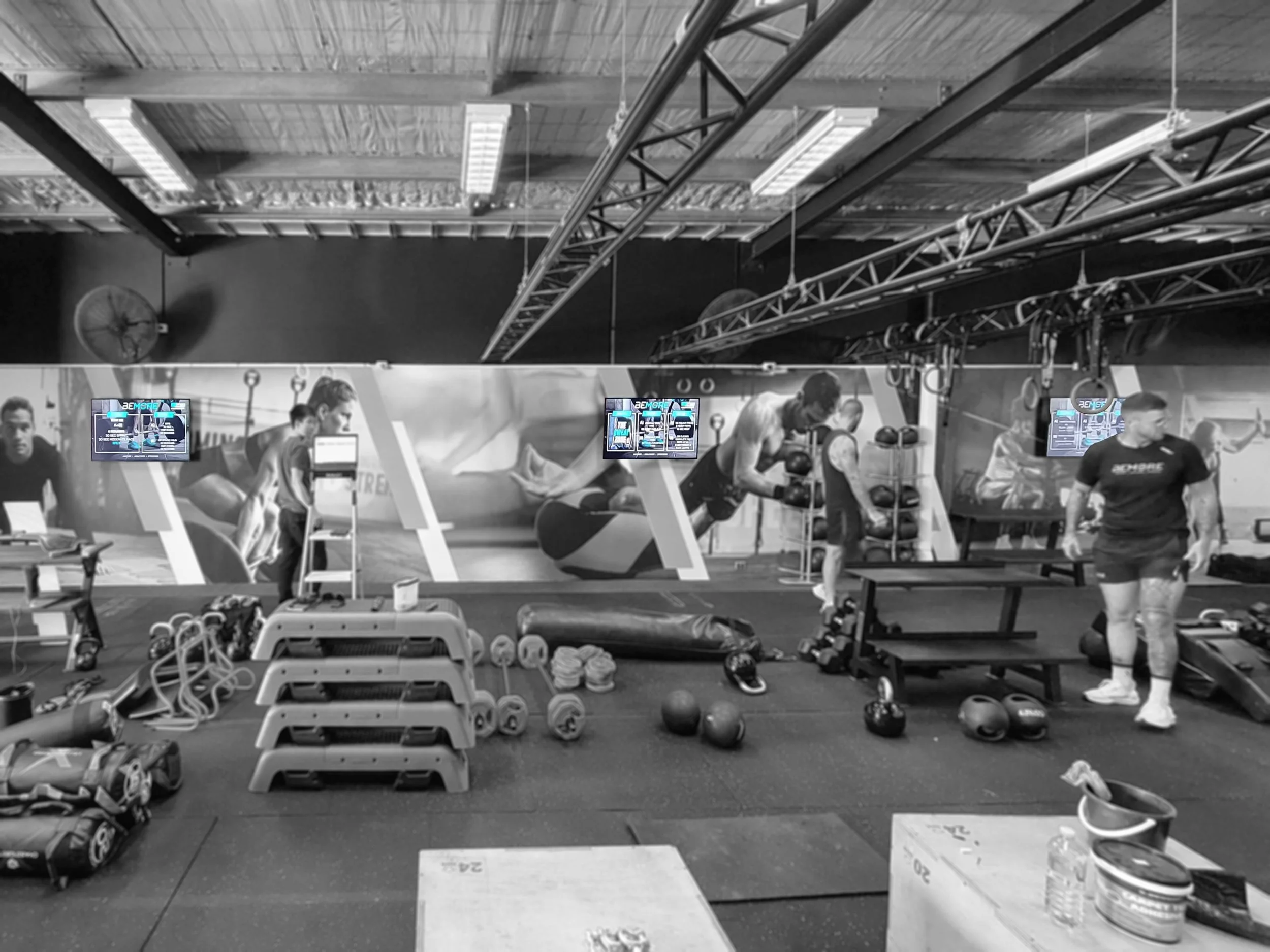Three wall-mounted workout displays along a printed feature wall at Bemore Fitness, Perth.