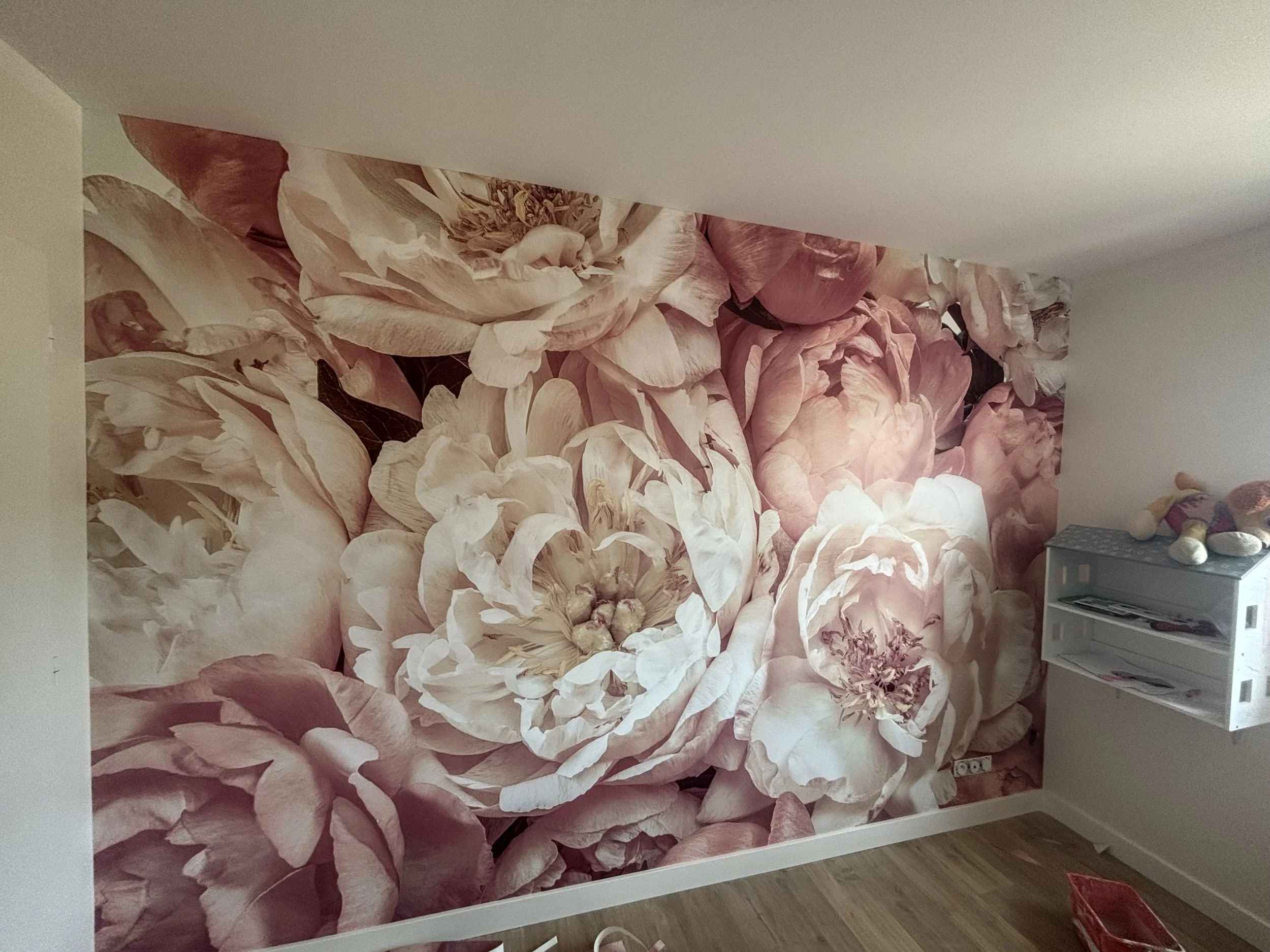 Mur en salle avec grande fresque florale de grosses roses roses et blanches.
