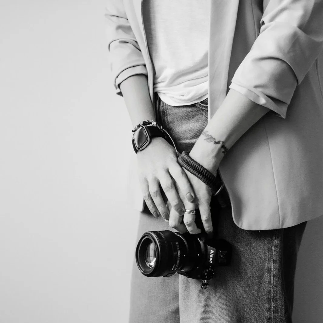 Fotografin mit Tattoo am Arm hält  Kamera in der Hand