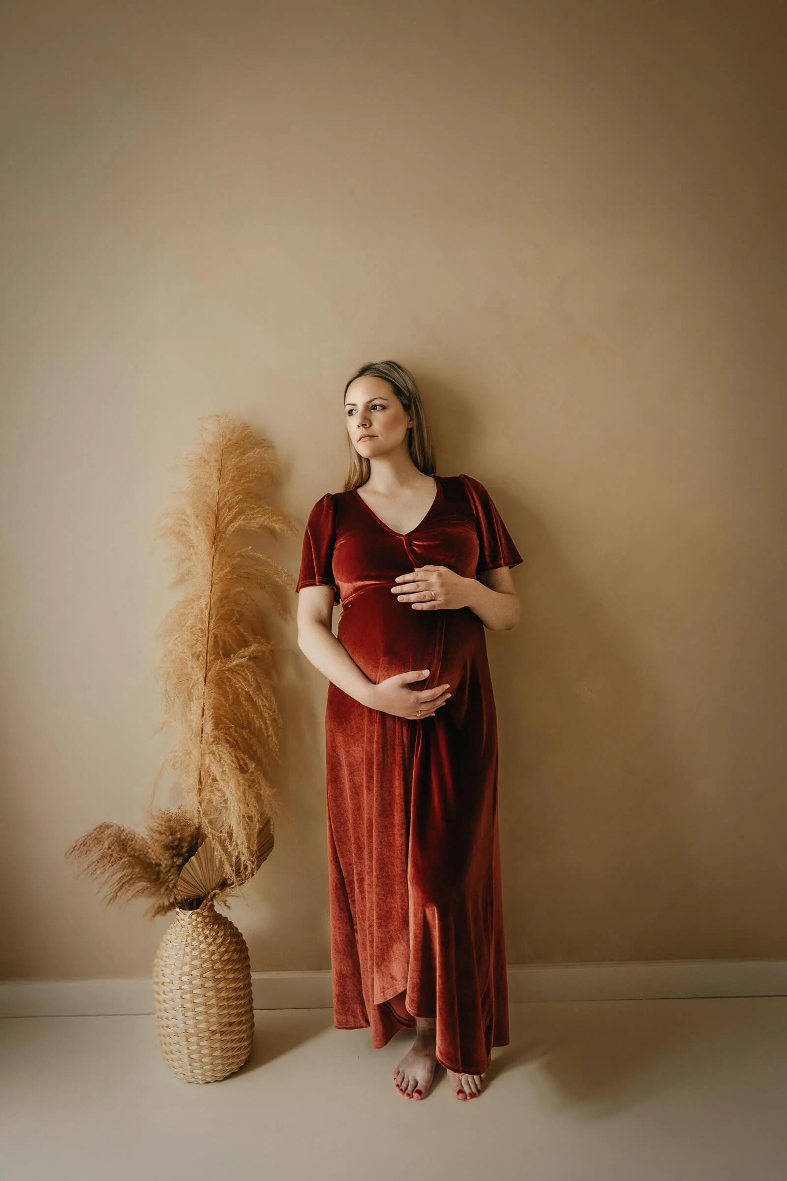 Babybauch Shooting Studio München – schwangere Frau im roten Samtkleid mit Boho Deko, Ela Behrens Fotografin