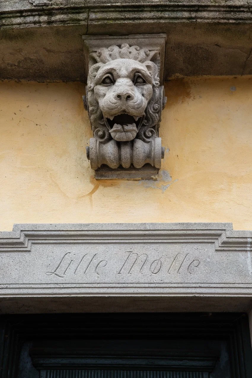 An antique stone lion sculpture on the historic wall of Lille Moelle, part of the museum mystery experience.