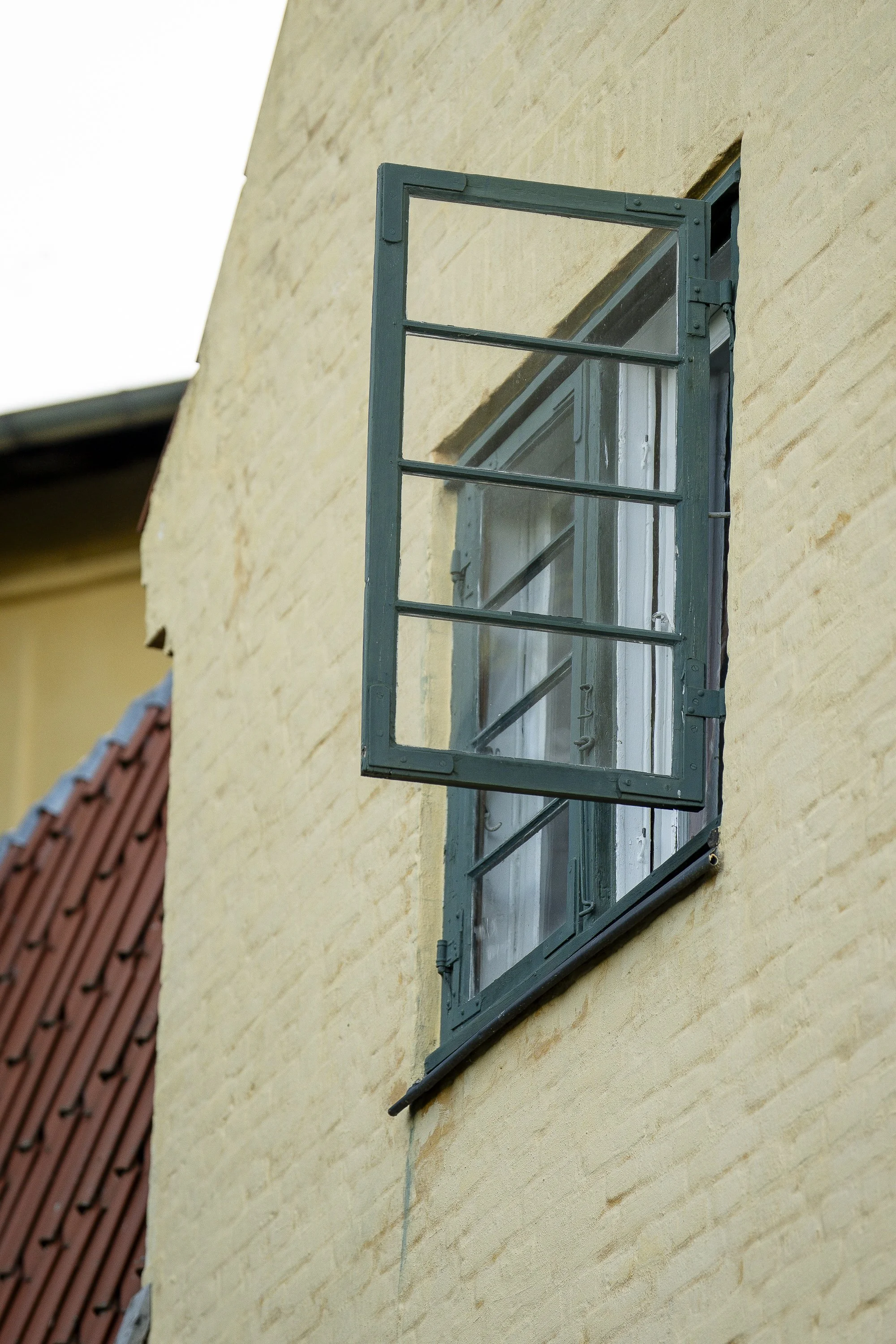 Close-up of a charming historic window and yellow brick wall at Lille Moelle, offering a calm setting for meditation.