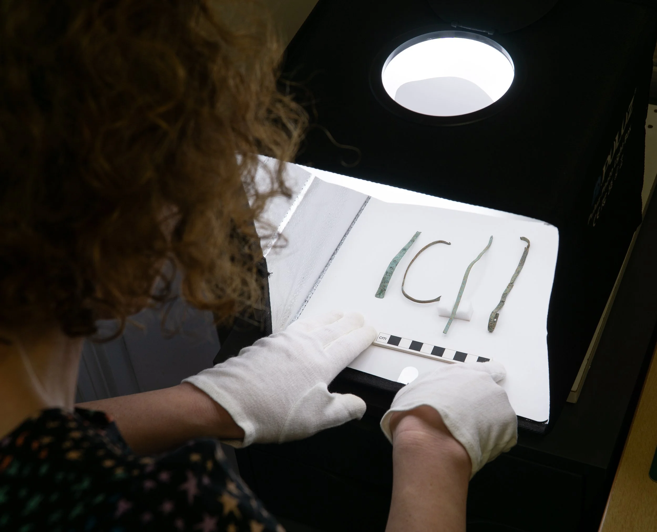 Broken pieces of decorated chocolate with a centimeter scale for size reference.