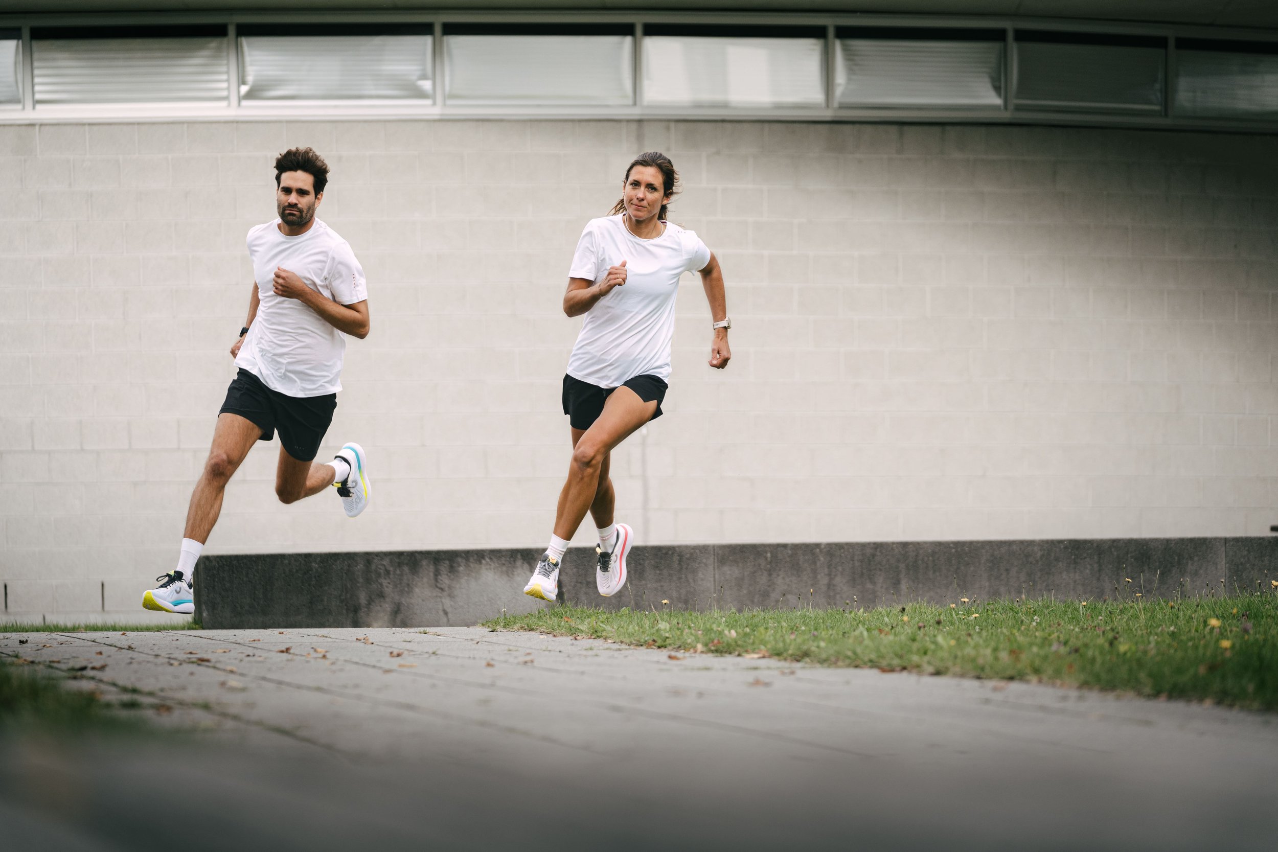Zwei Personen joggen im Freien nebeneinander auf einem Weg.
