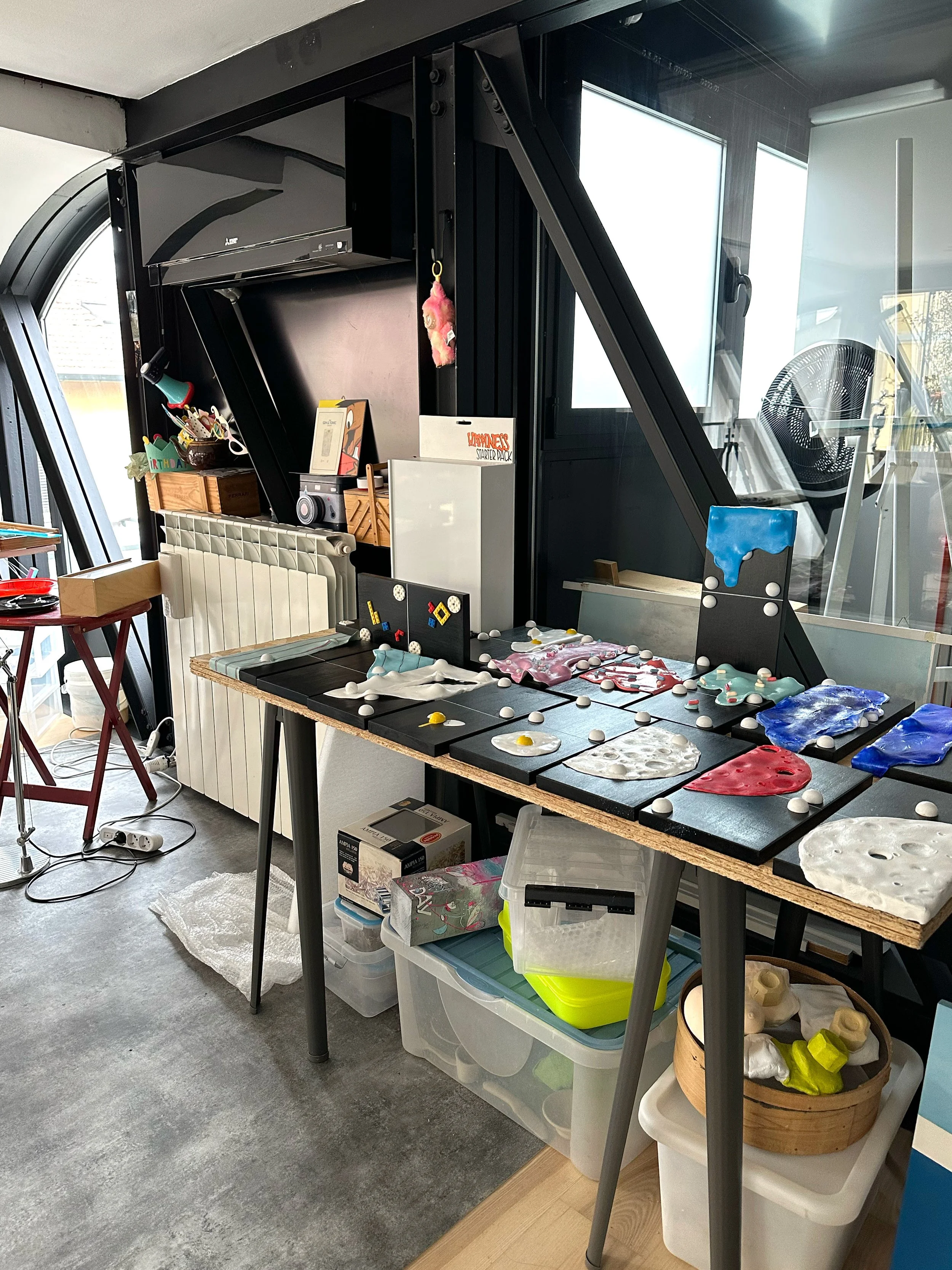 Estudio de Vera Vizzi con numerosos relieves escultóricos de colores dispuestos sobre una mesa.