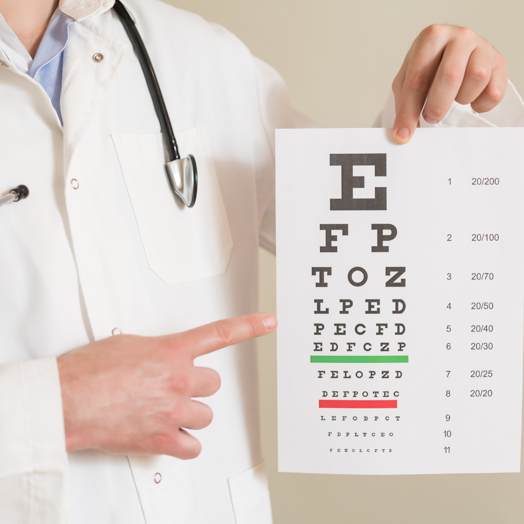 A healthcare professional in a white coat holding an eye chart for vision testing, pointing at the fourth line.
