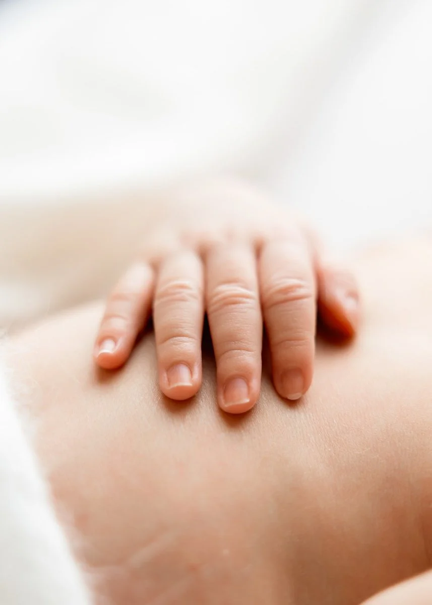 Nahaufnahme einer Babyhand auf Babybauch