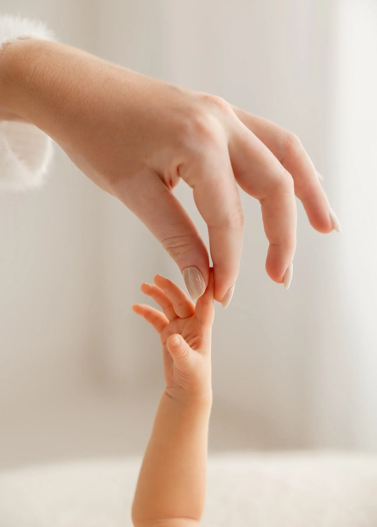 Eine erwachsene Hand hält vorsichtig die kleine Hand eines Babys.