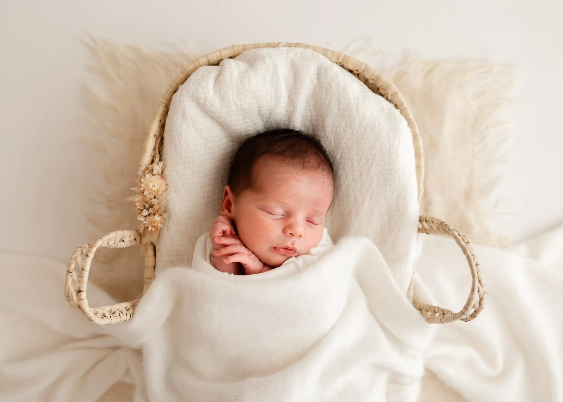 Schlafendes Baby in einem Korb mit weißer Decke.