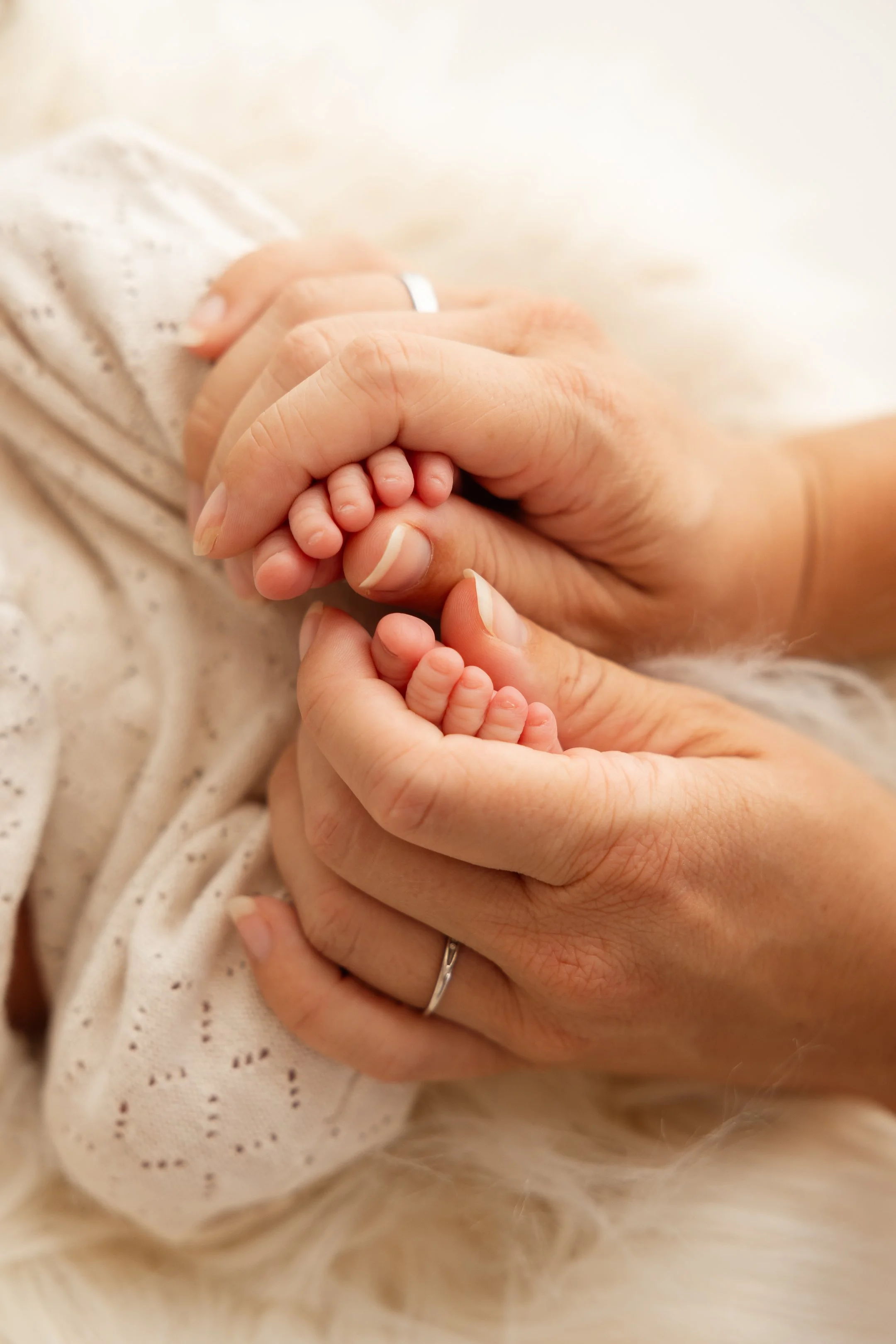 Hände eines Erwachsenen, die die winzigen Füße eines Babys halten.