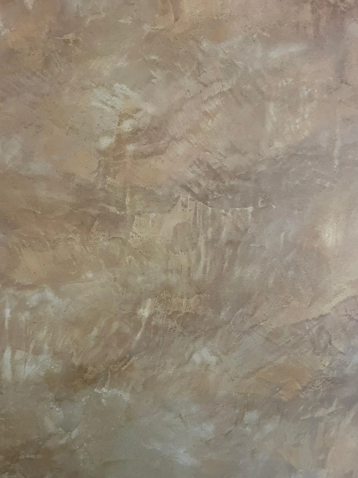 Close-up photo of a polished clay plaster wall surface in beige and brown.