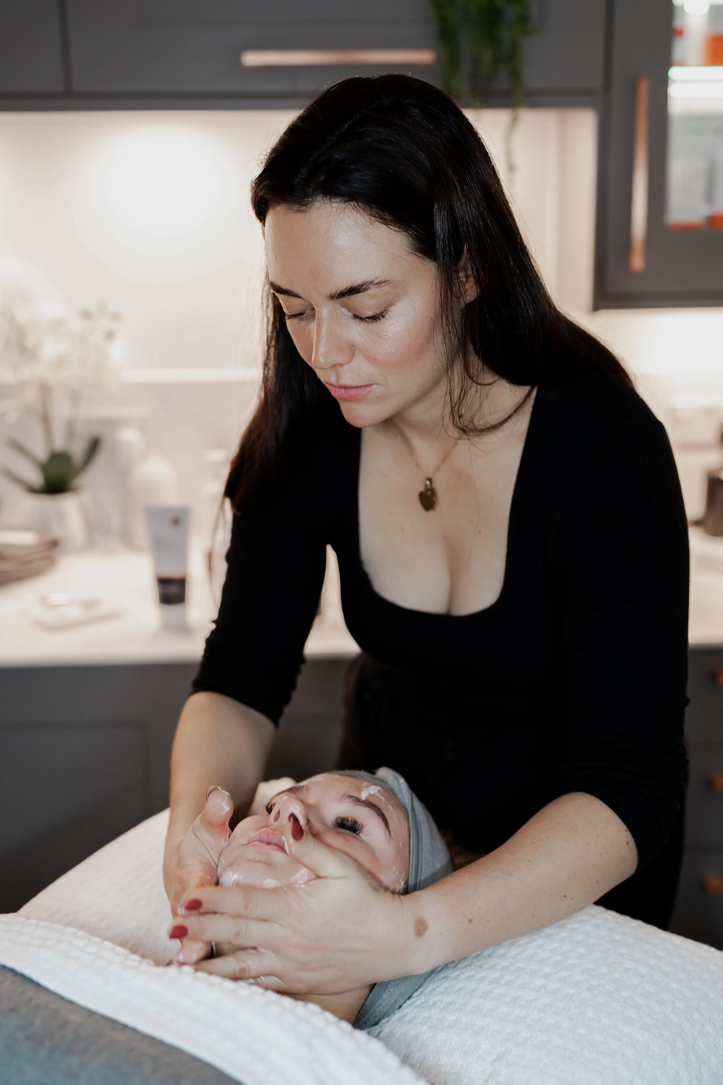 Aesthetician giving a facial treatment to a client in a spa setting.