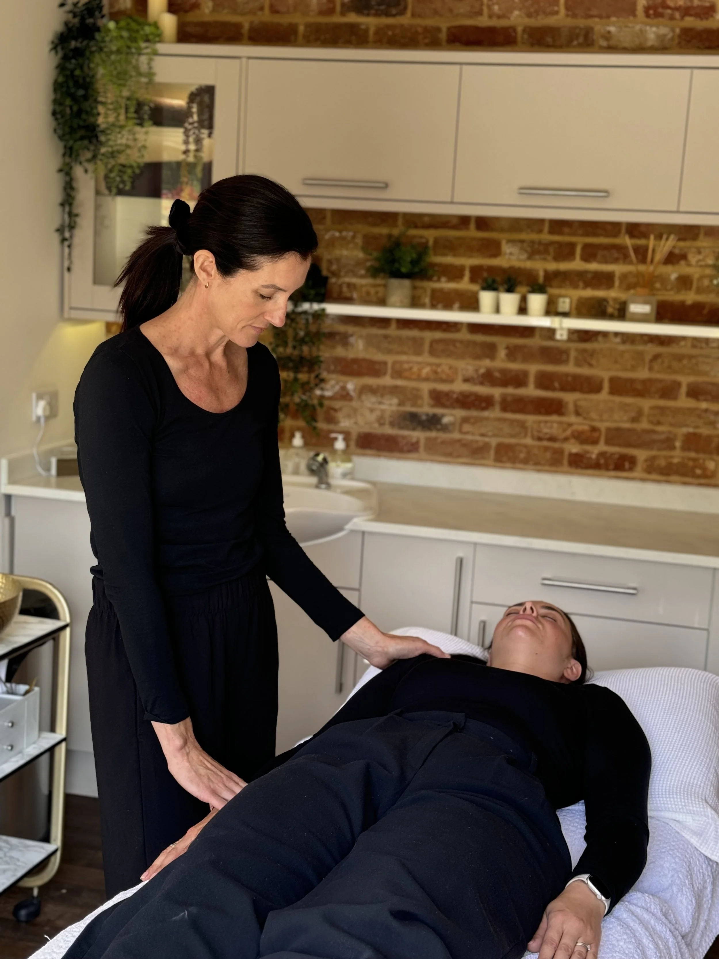 A therapist performing a relaxing treatment on a person lying down in a wellness center.