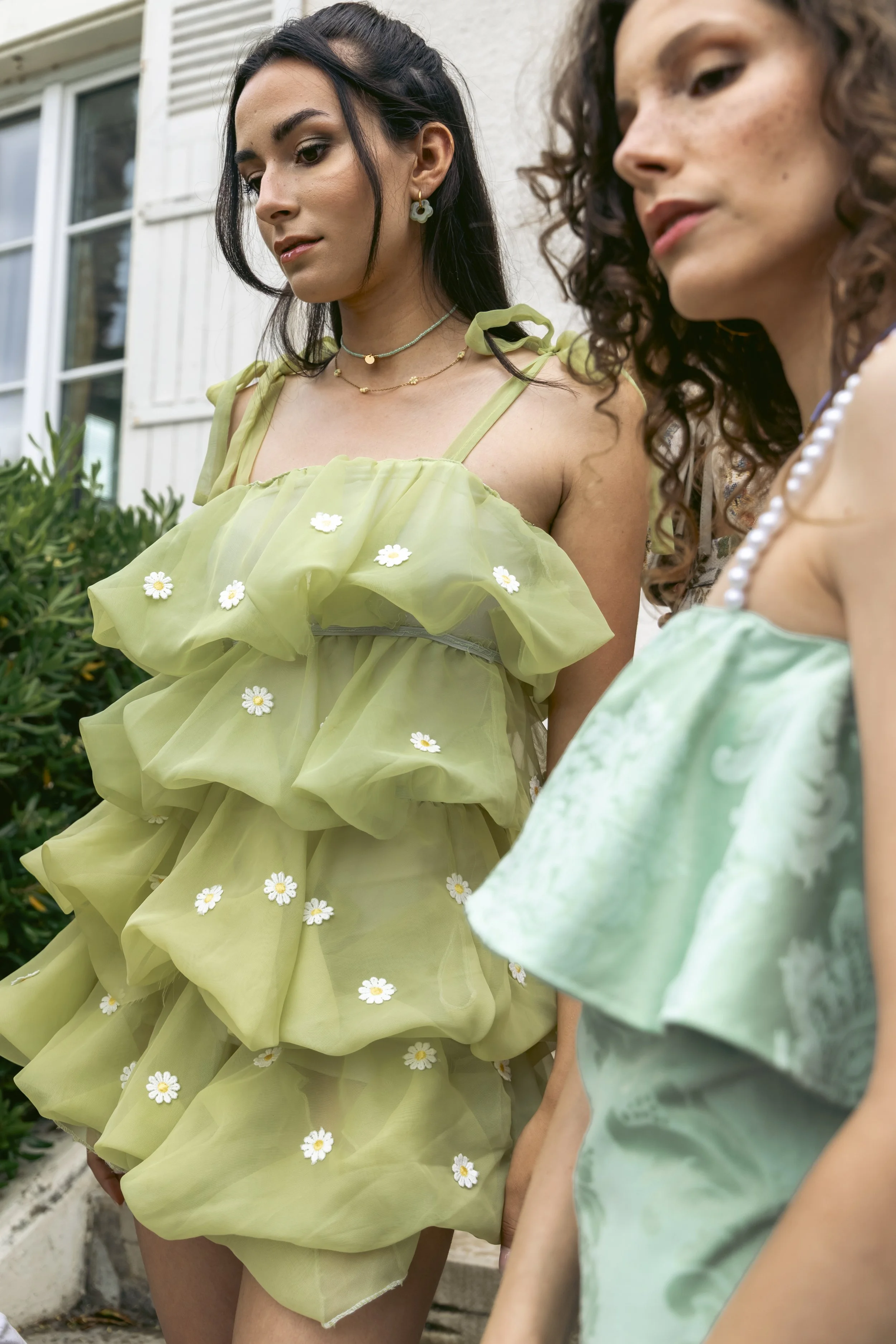 Deux femmes enceintes portant des robes vert clair, décorées de petites fleurs blanches, se tenant par la main