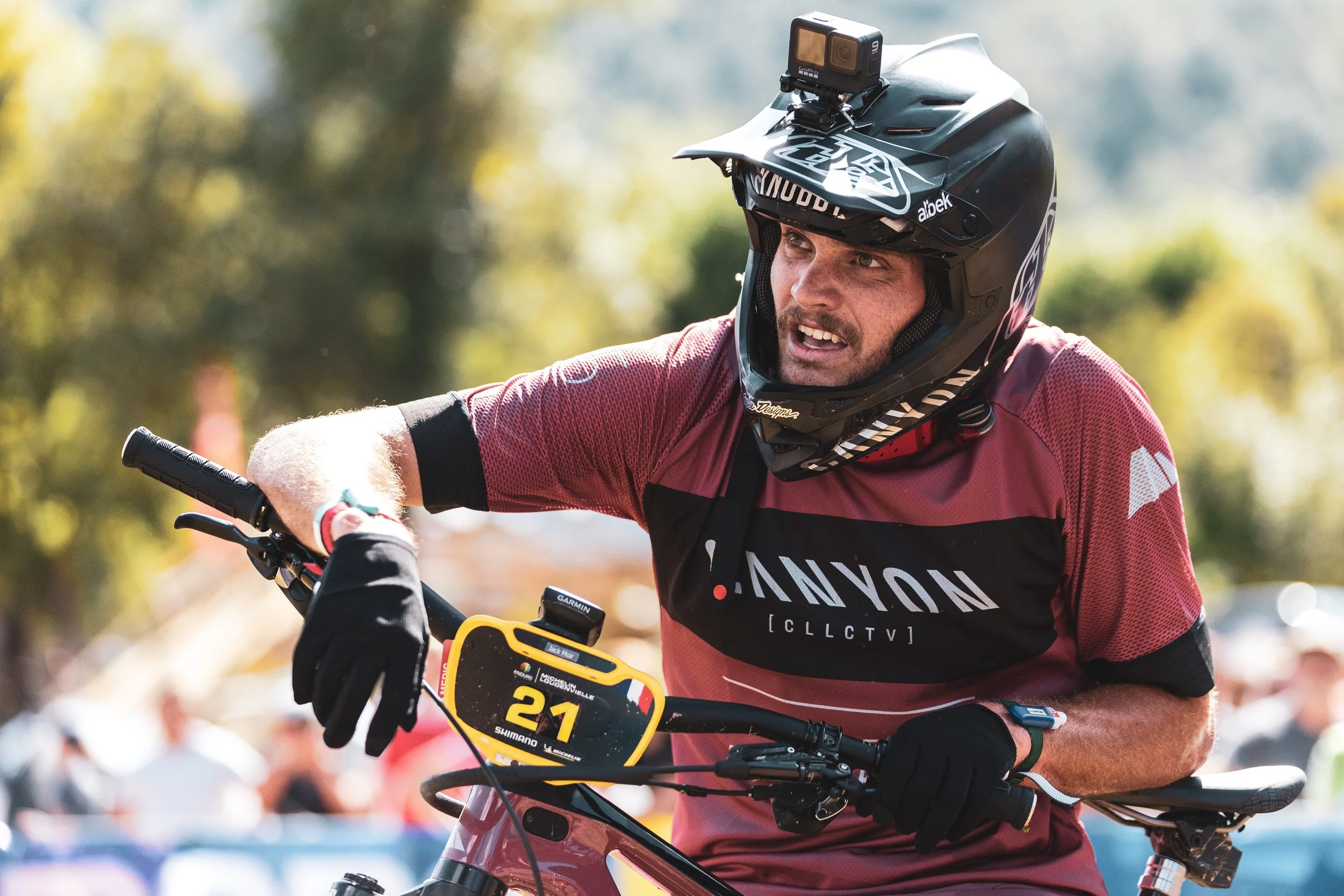Un homme portant un casque de moto tout-terrain et un maillot de couleur rouge participe à une compétition de VTT.