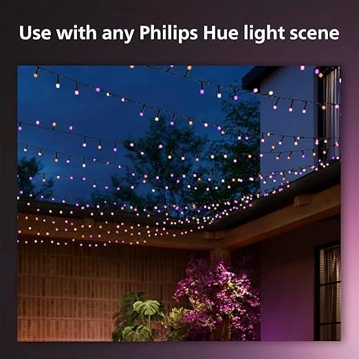 Outdoor patio decorated with string lights in purple and warm colors, set against a dark evening sky with trees and house in the background.